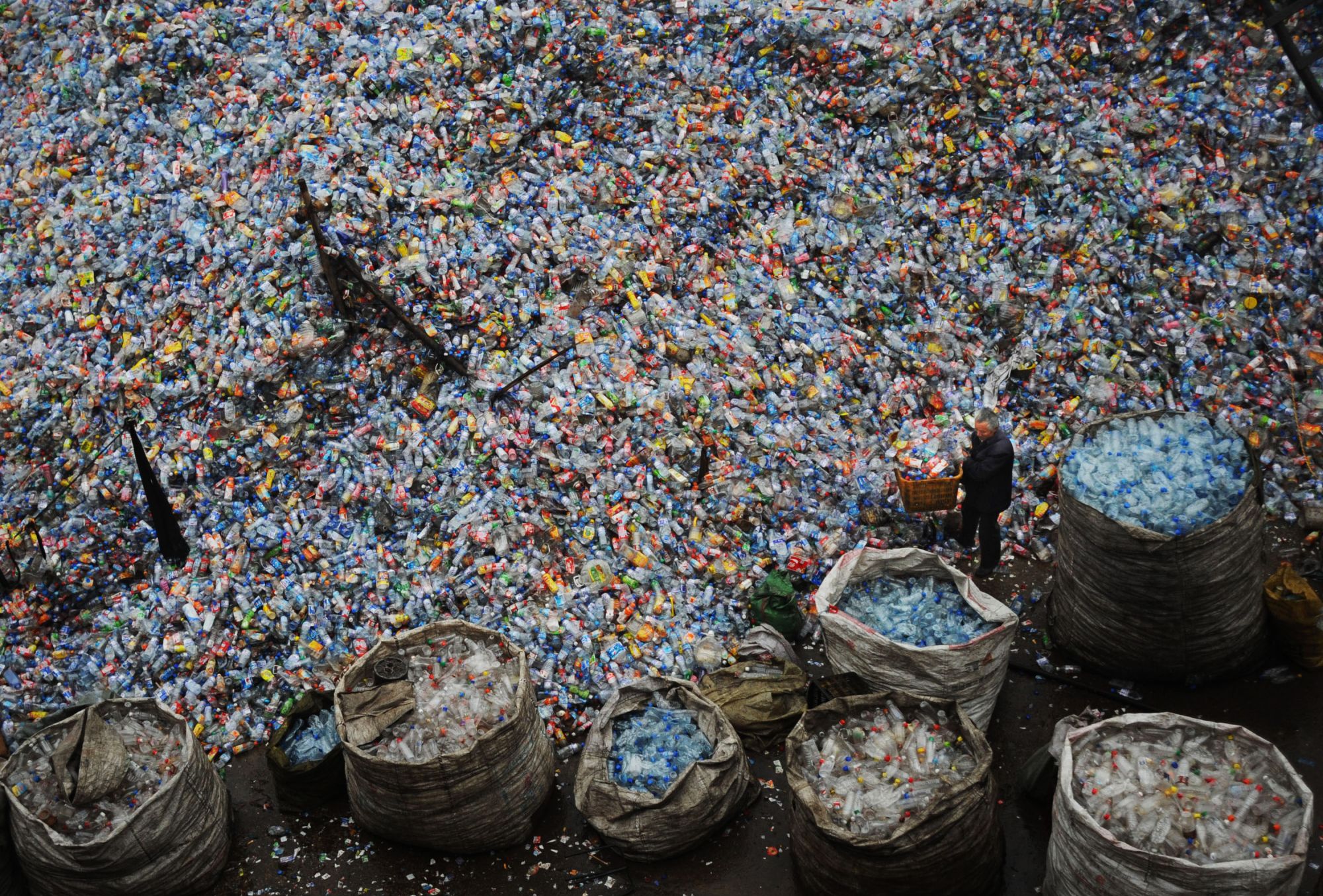 WUHAN, CHINA - OCTOBER 29: (CHINA OUT) A worker sorts used plastic bottles at a plastics recycling mill which is ceasing production as the global financial crisis starts to bite in China's recycling industry on October 29, 2008 in Wuhan of Hubei Province, China. Many of China's recycling mills and farms are being forced to stop collecting recyclable scrap materials due to the nose-diving order prices as those of oil, metal and other commodities have plunged worldwide amid a worsening economic outlook.  (Pho