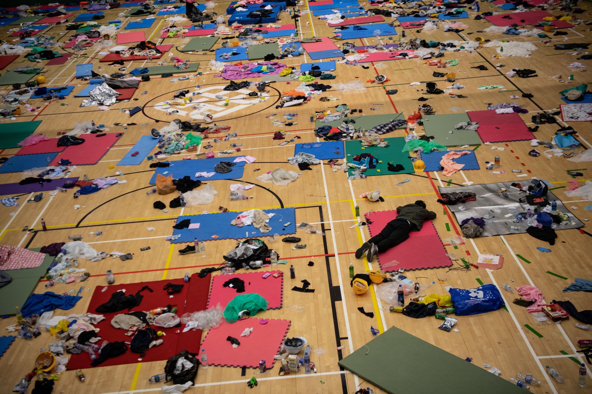 HONG KONG, CHINA - NOVEMBER 21: A man sleeps in a gym that is strewn with abandoned belongings at Hong Kong Polytechnic University, which has been taken over by anti-government protesters, on November 21, 2019 in Hong Kong, China. Anti-government protesters armed with bricks, firebombs, and bows and arrows fought with the police at university campuses over the past week as demonstrations in Hong Kong stretched into its sixth month with demands for an independent inquiry into police brutality, the retraction