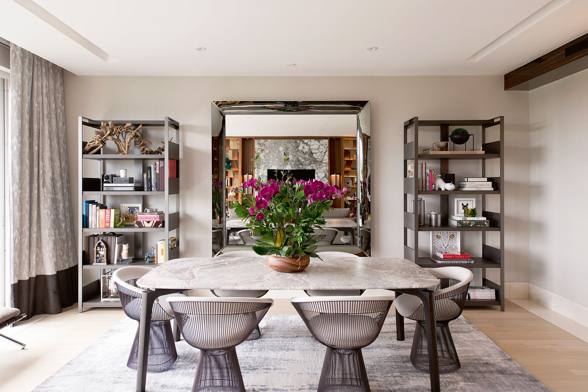 A pair of shelves and the set of six Knoll Platner dining chairs contribute to the pleasing symmetry in the dining area