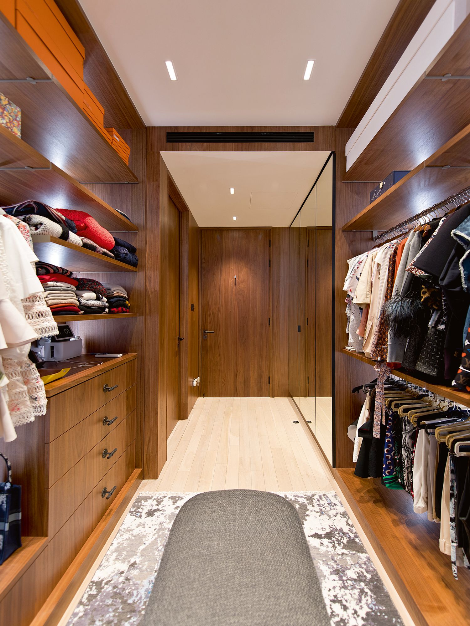 The grey bench and rug add a plush touch to the wardrobe area