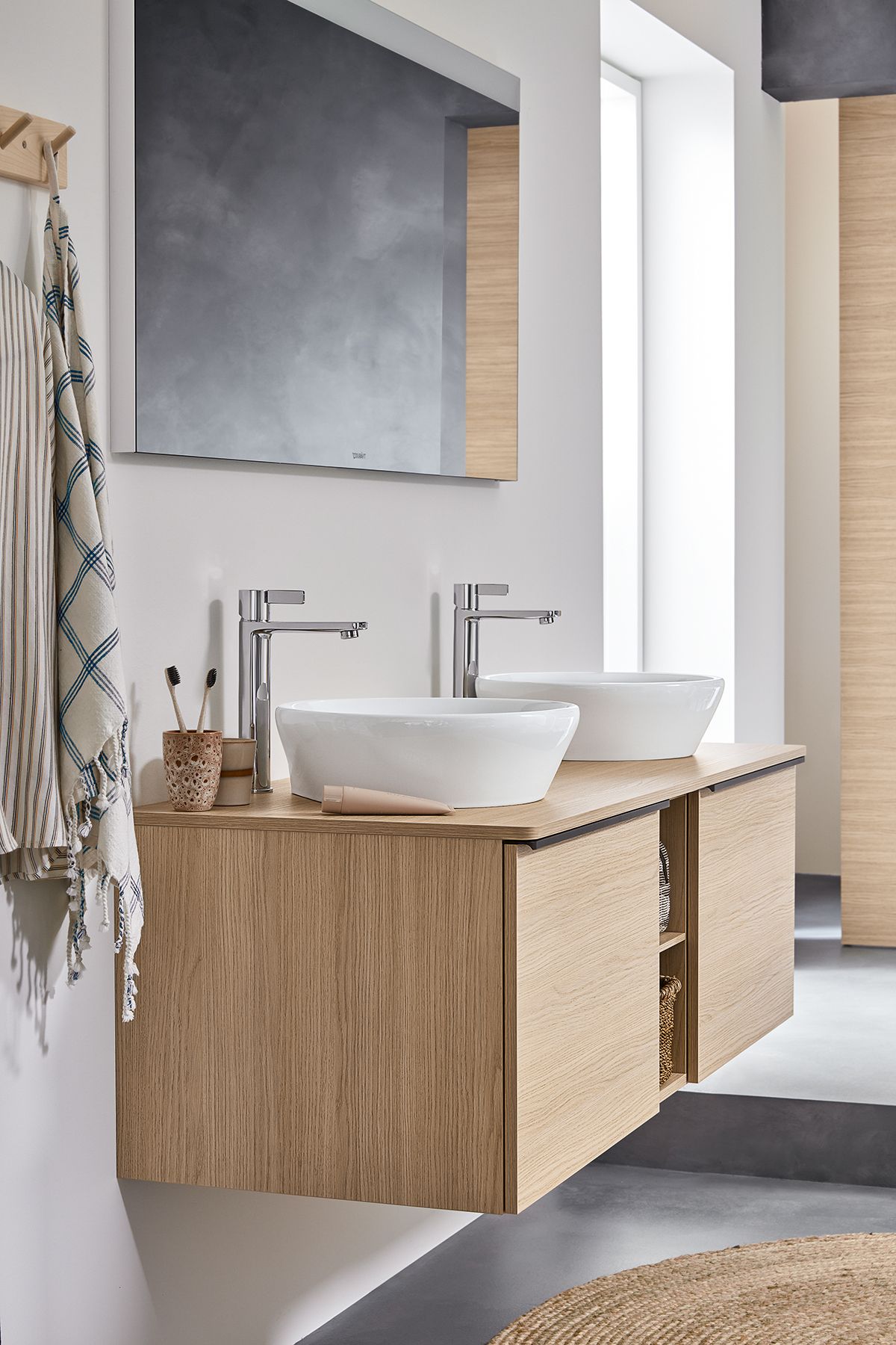 Ample storage: the wall-mounted vanity unit provides practical storage space with two drawers, a matching divider, and two open racks. The round above-counter wash bowls (diameter of 400 mm) can be positioned side-by-side or solo.
