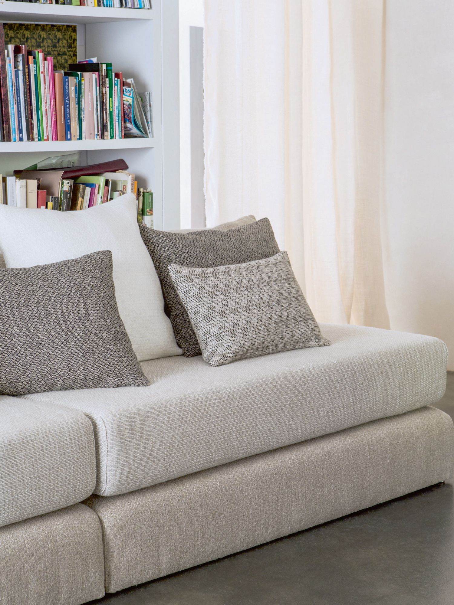A sofa and accent cushions upholstered in fabrics from the Élitis Pur Lin upholstery collection