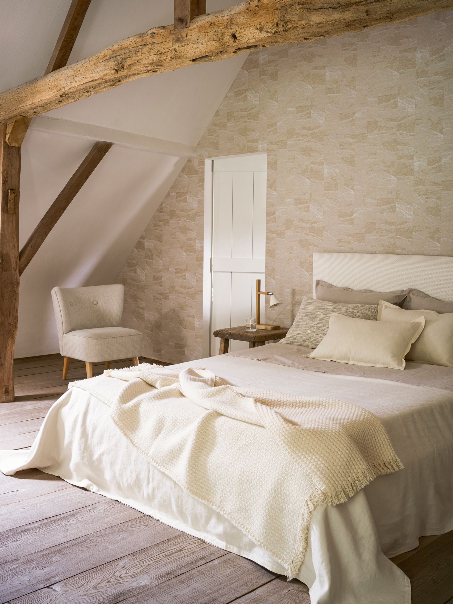A bedroom dressed in upholstery textiles and wallpaper from Pierre Frey’s Natecru collection