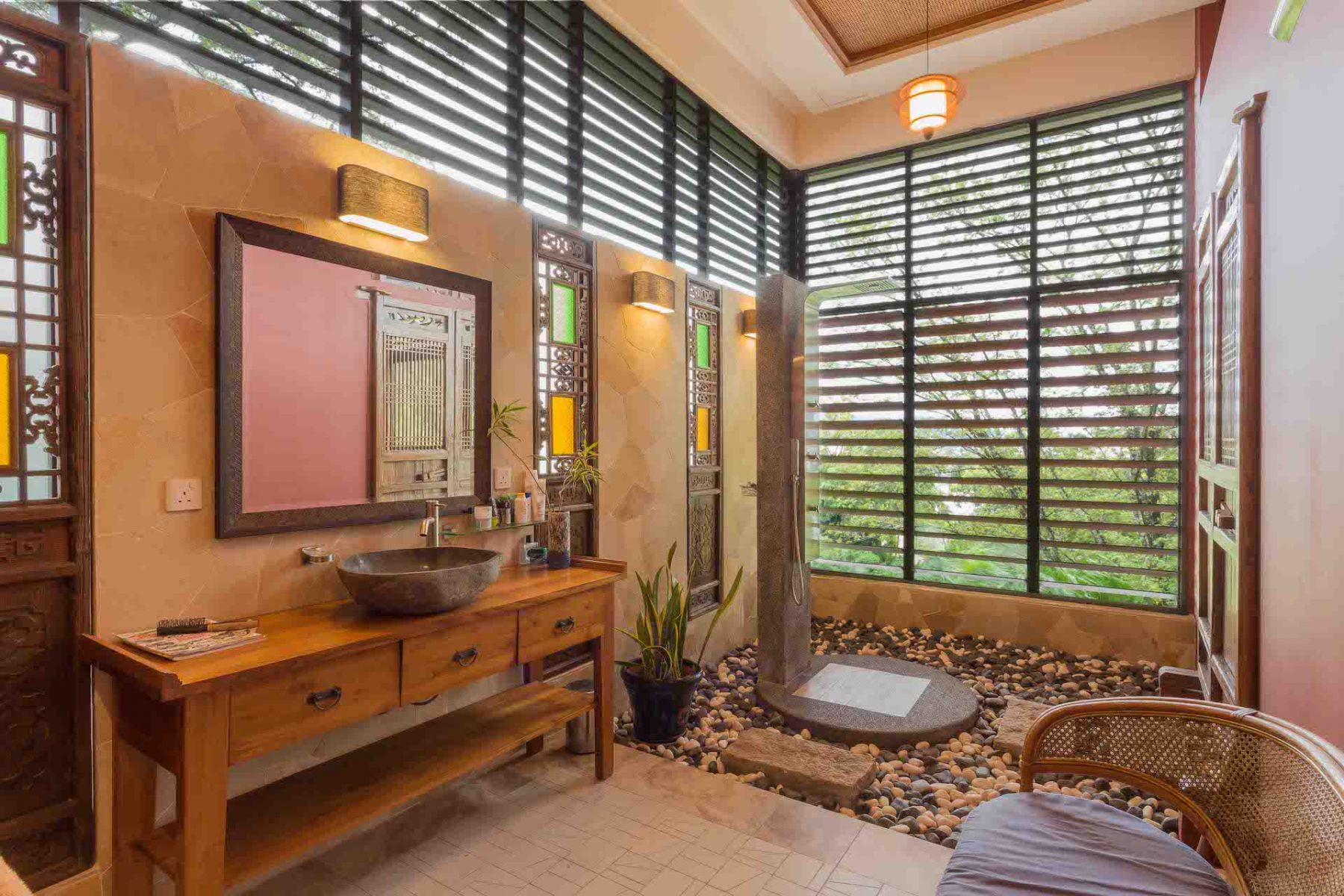 The open bathroom has large windows but louvers to preserve privacy