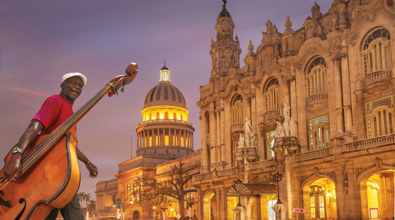 "Hispanic musician carrying upright bass in city, Havana, Cuba"