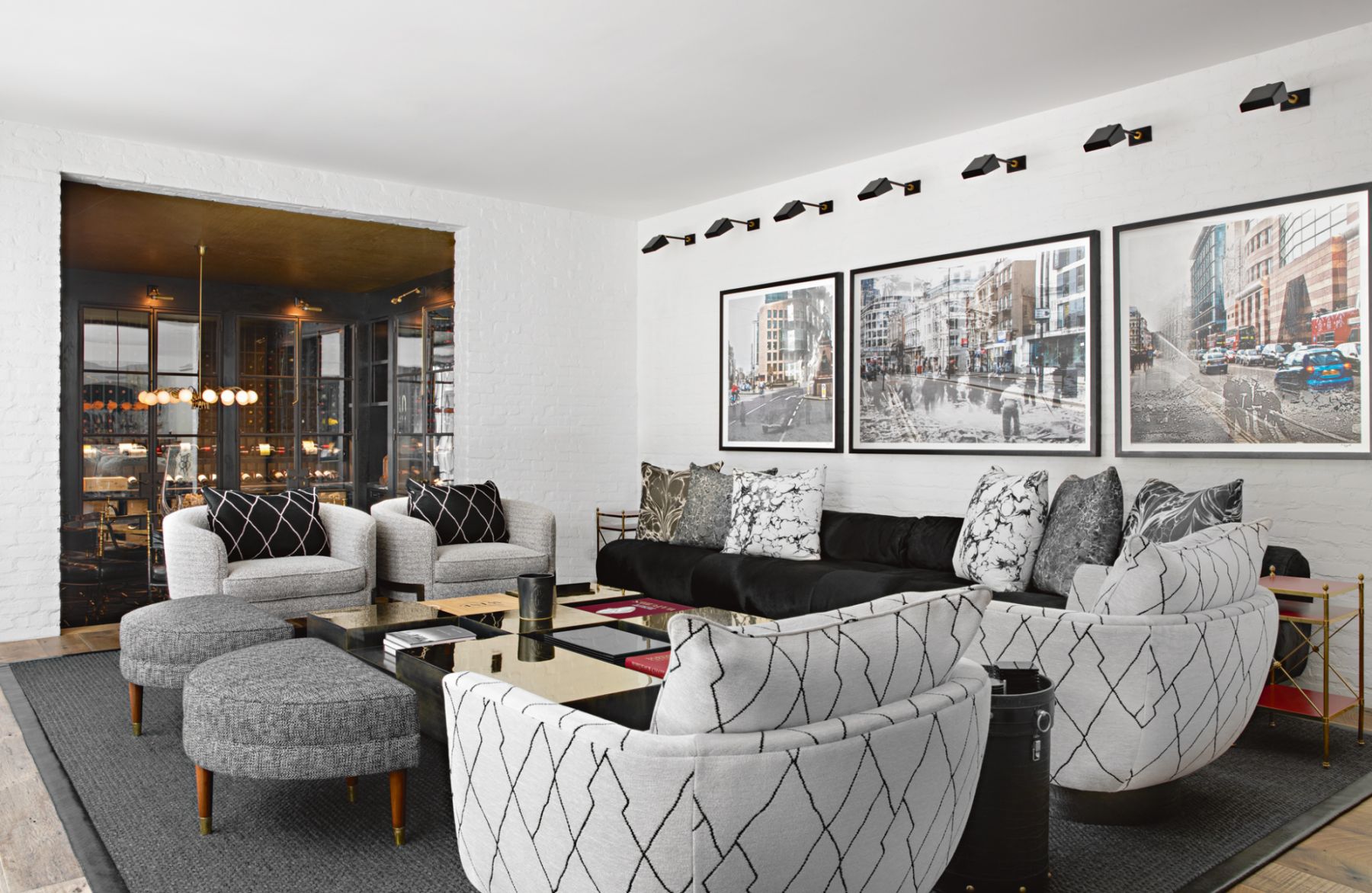 The family room features a row of Urban Archeology lights on the gallery wall and a bronze coffee table with various compartments for books and collectibles