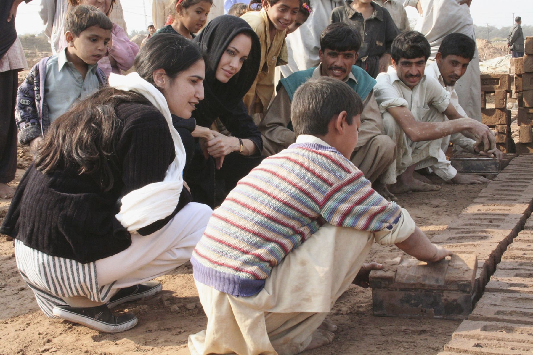 ISLAMABAD, PAKISTAN - NOVEMBER 26: In this handout photo supplied by the United Nations High Commission for Refugees (UNHCR), UNHCR Goodwill Ambassador Angelina Jolie visits a brick kiln on the outskirts of Islamabad that she visited in May 2005, to follow up on the situation of Afghan children working there, November 26, 2005 in Islamabad, Pakistan. (Photo by J Redden/UNHCR via Getty Images)