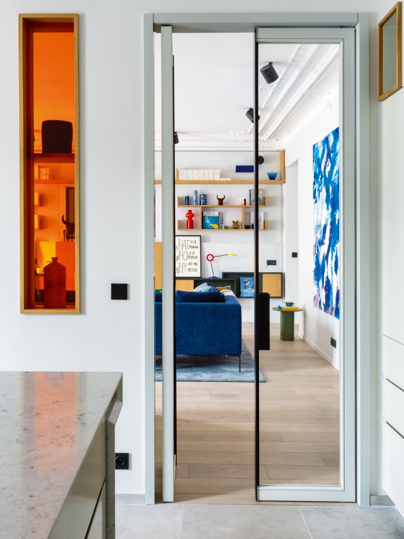 The orange glass insert connects the living room to the kitchen