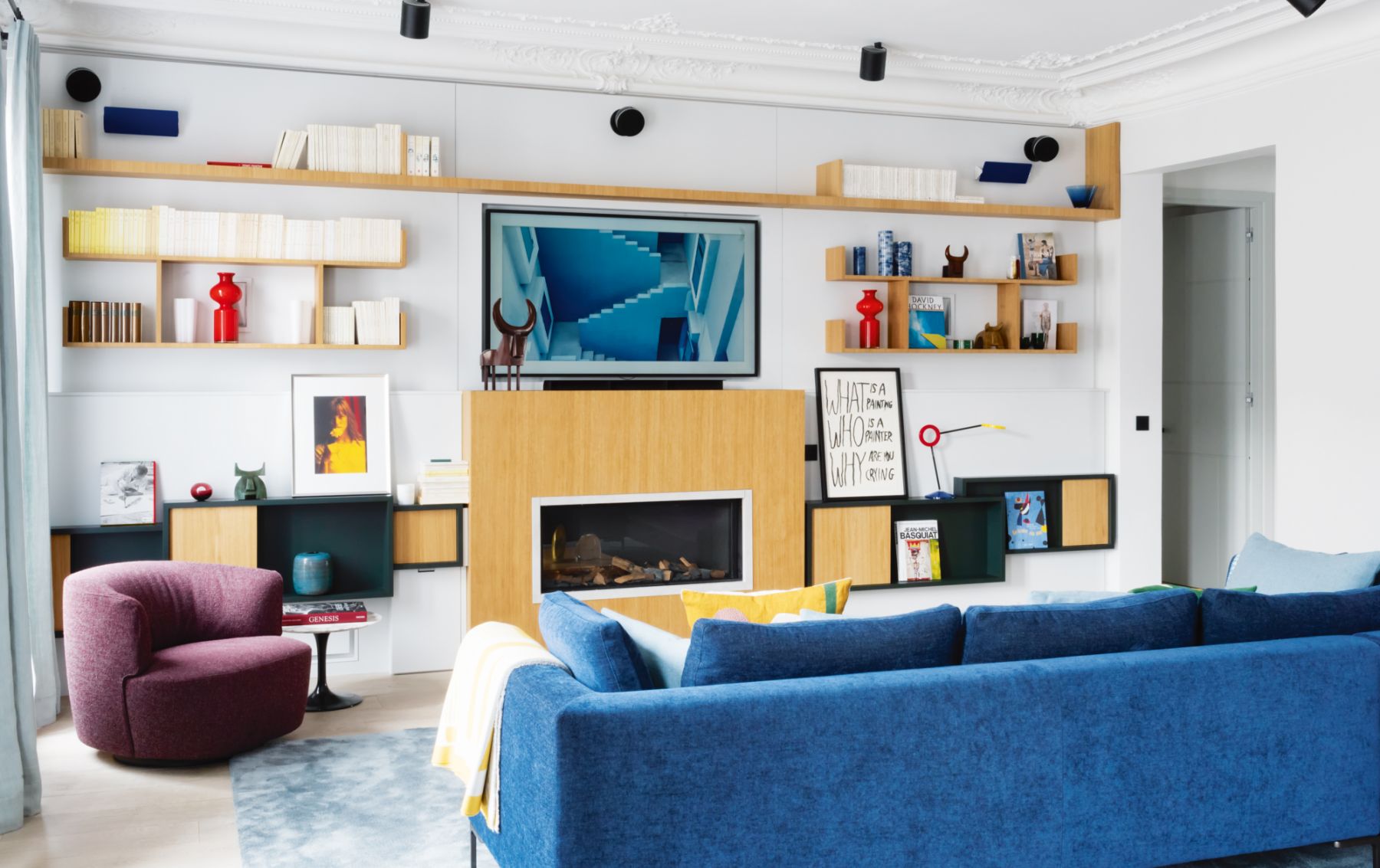 A custom-made gas fireplace stands at the heart of the living room, surrounded by shelves, books, vases and other decorative object