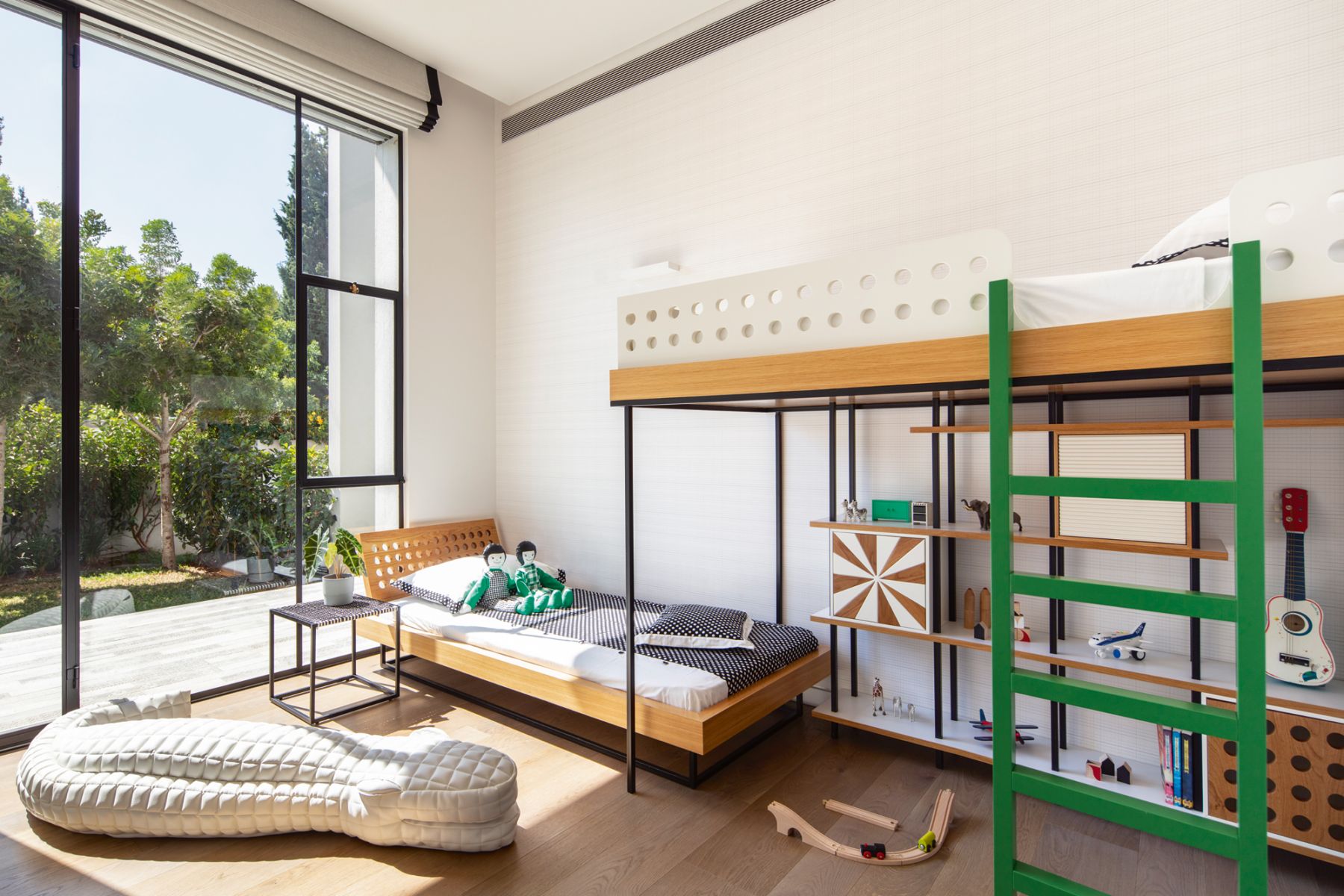 This bedroom designed by Sarit Shani Hay features a minimalist scheme with green accents and playful display shelves