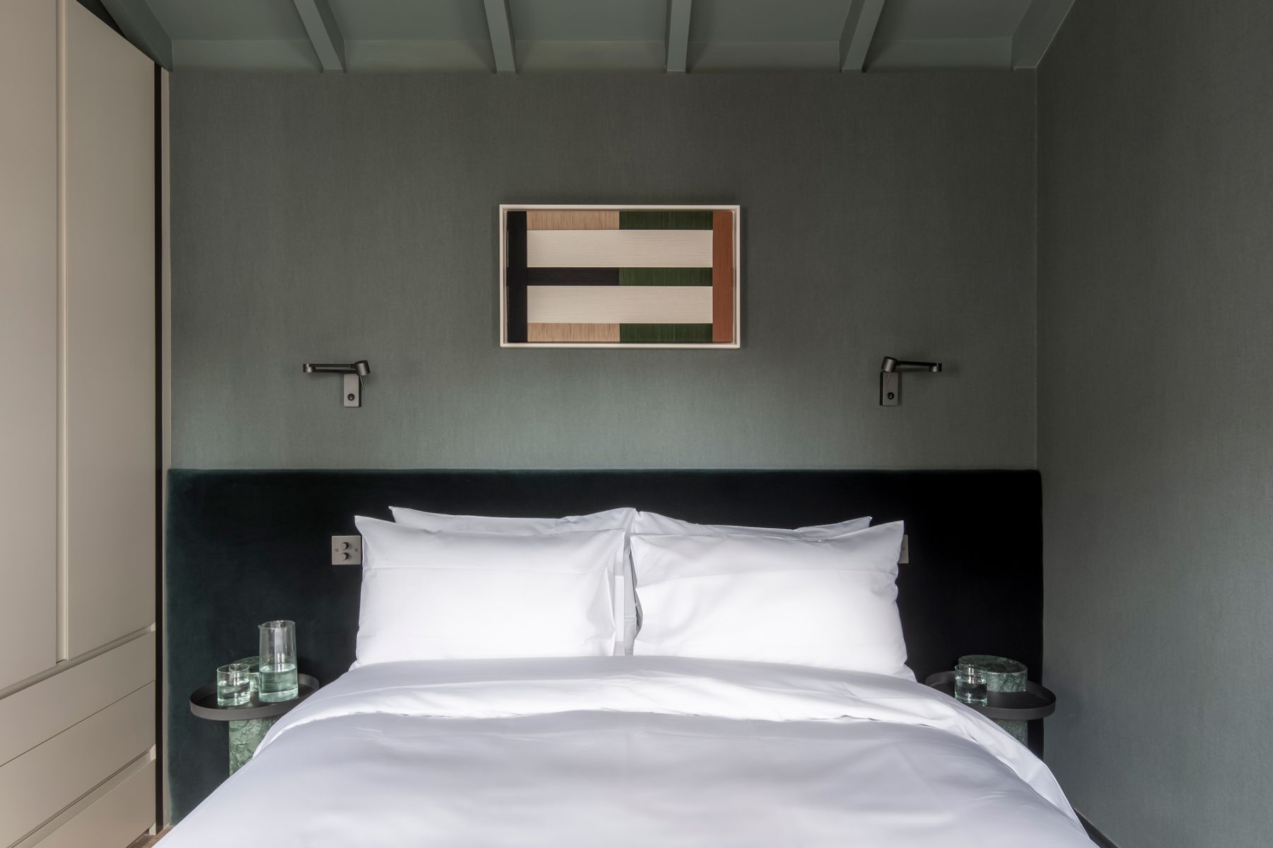 The master bedroom features various hues of green, including a textured linen wallpaper and velvet headboard