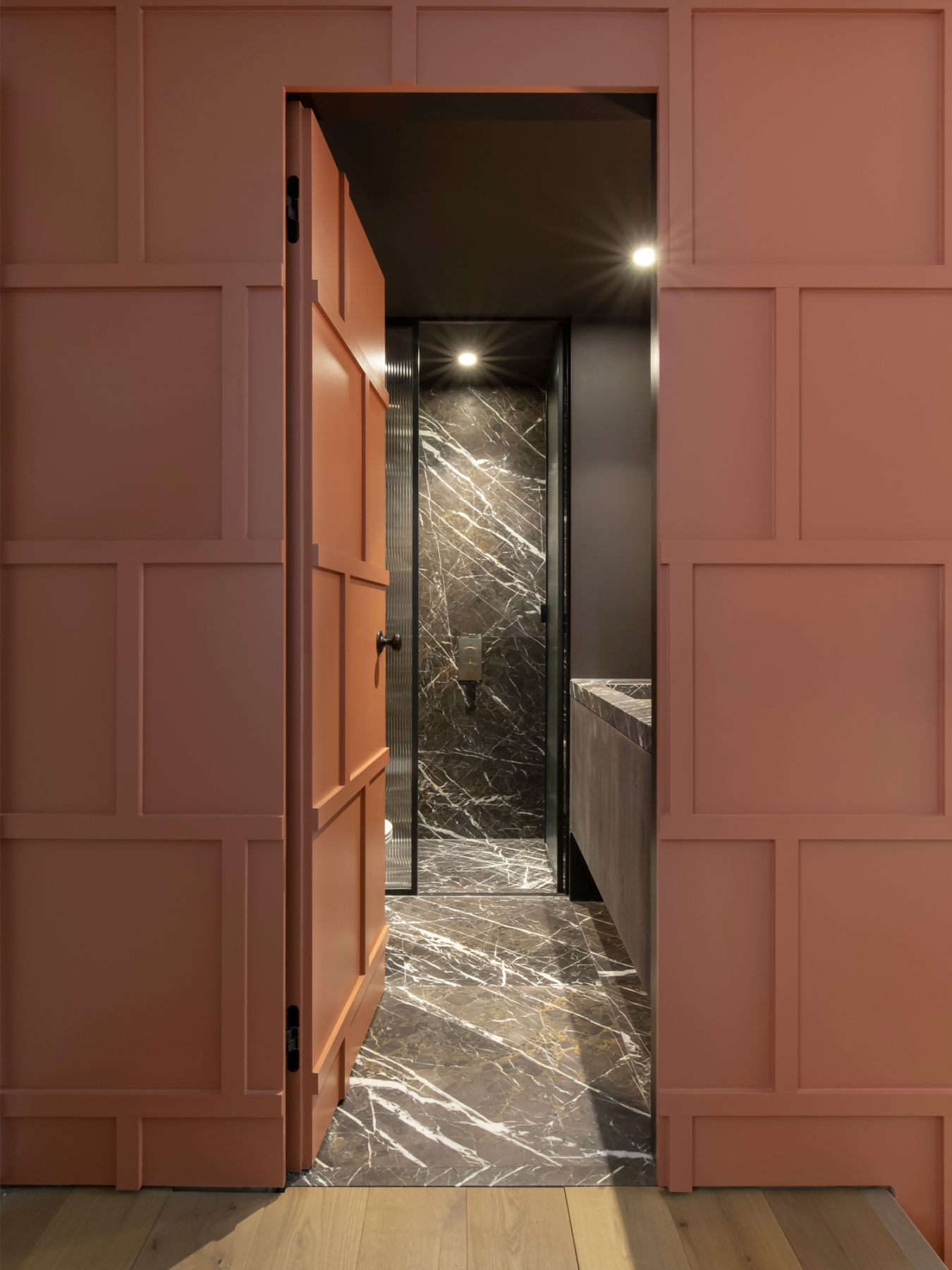 The terracotta-hued panelling leads the way to the guest bathroom