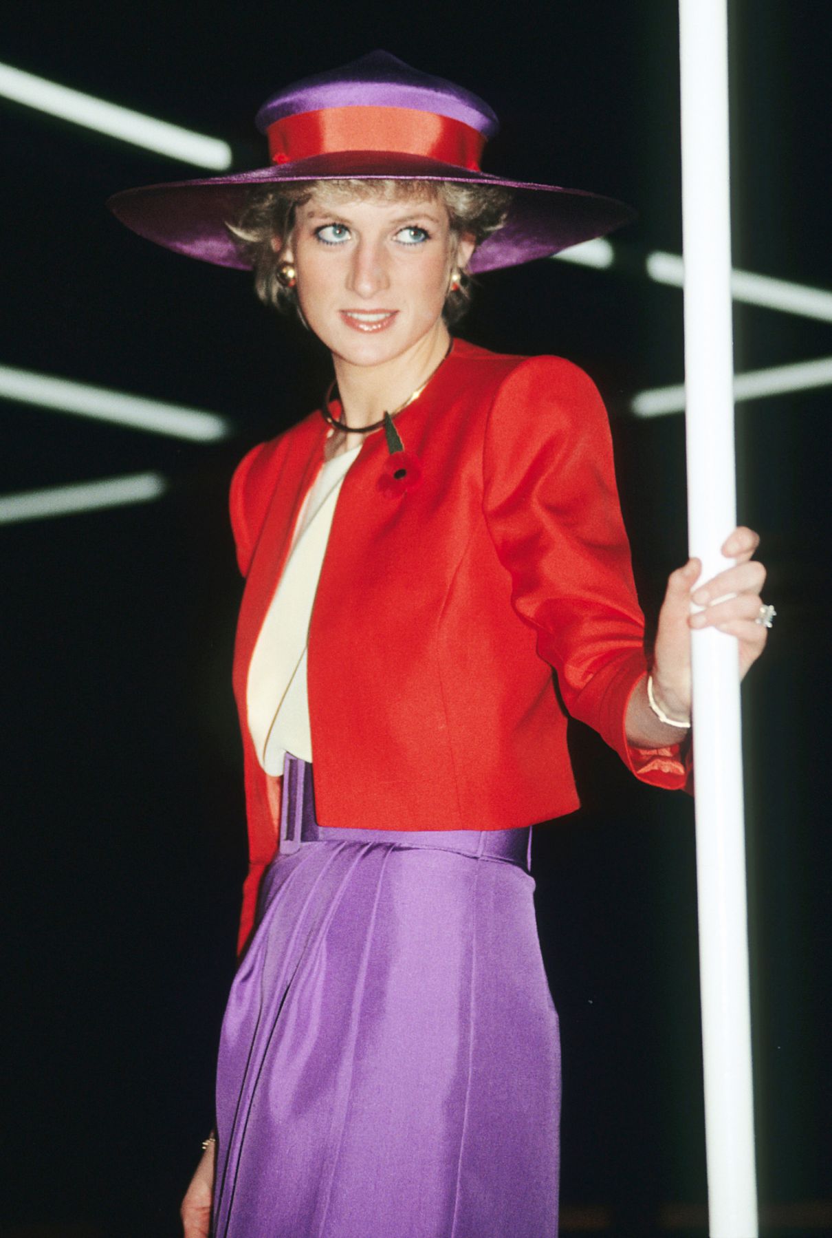 HONG KONG, CHINA - NOVEMBER 07: Diana, Princess of Wales, wearing a red and purple suit designed by Catherine Walker with a matching hat and remembrance poppy, arrives on the Governor's launch on November 7, 1989 in Hong Kong, China. (Photo by Anwar Hussein/WireImage)