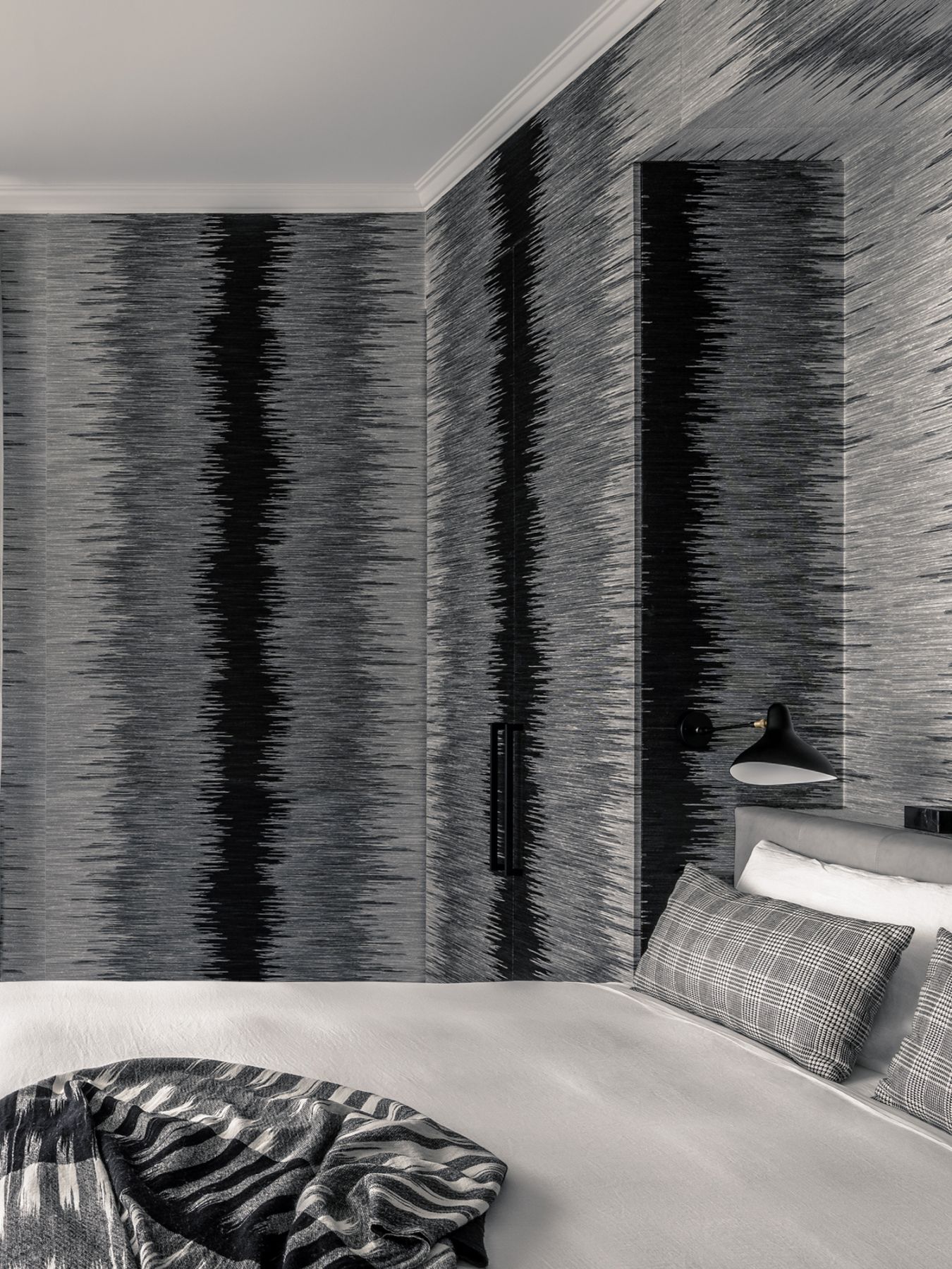 The guest bedroom features a monochromatic scheme with the Aragon wallpaper from Jim Thompson, alongside the custom-designed bed that's upholstered in leather