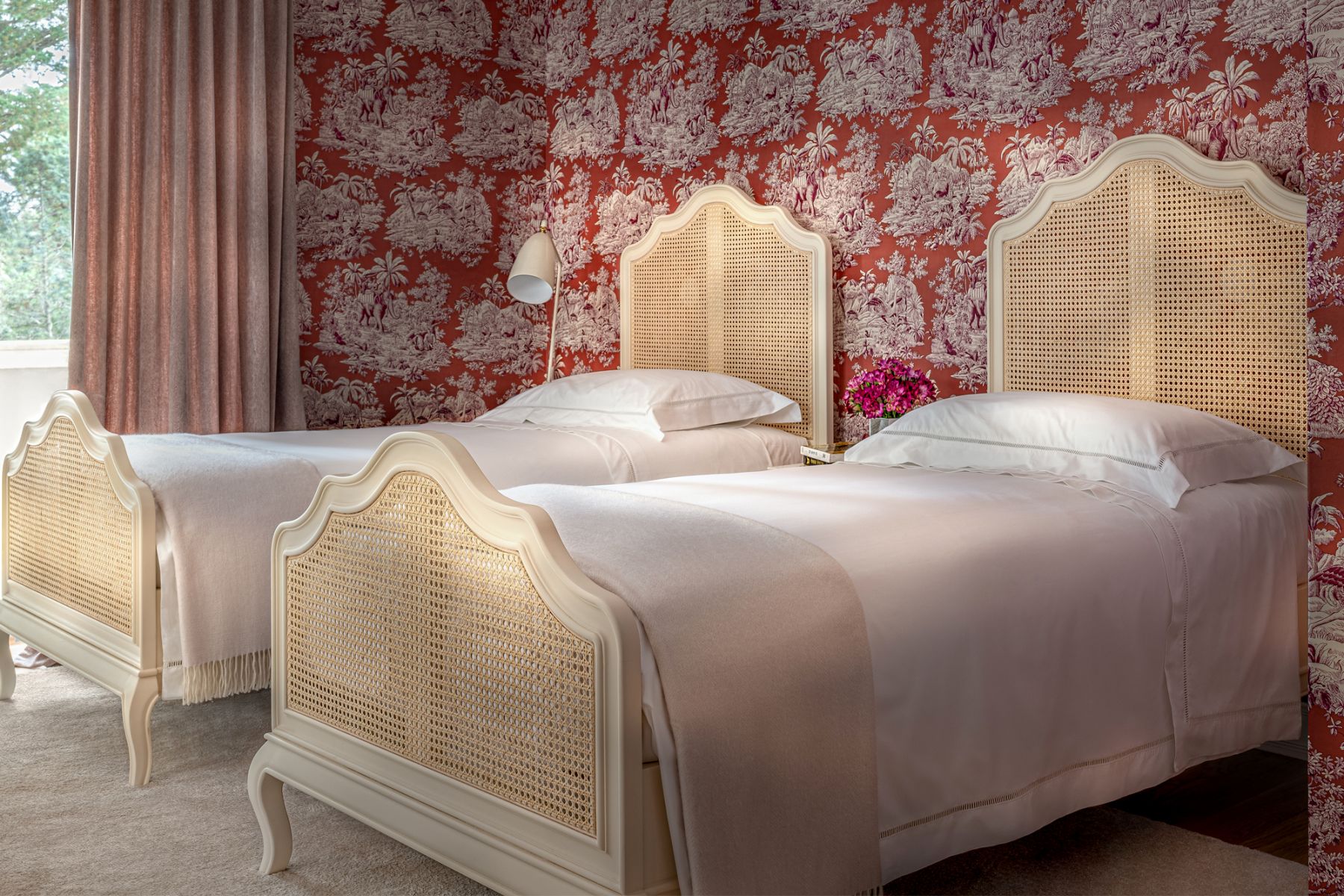 The children's suite features a red variation of the Trianon wallpaper from Manuel Canovas, which creates a comforting setting for the Grashoppa floor lamp from Gubi and the twin beds from Homes in Heaven