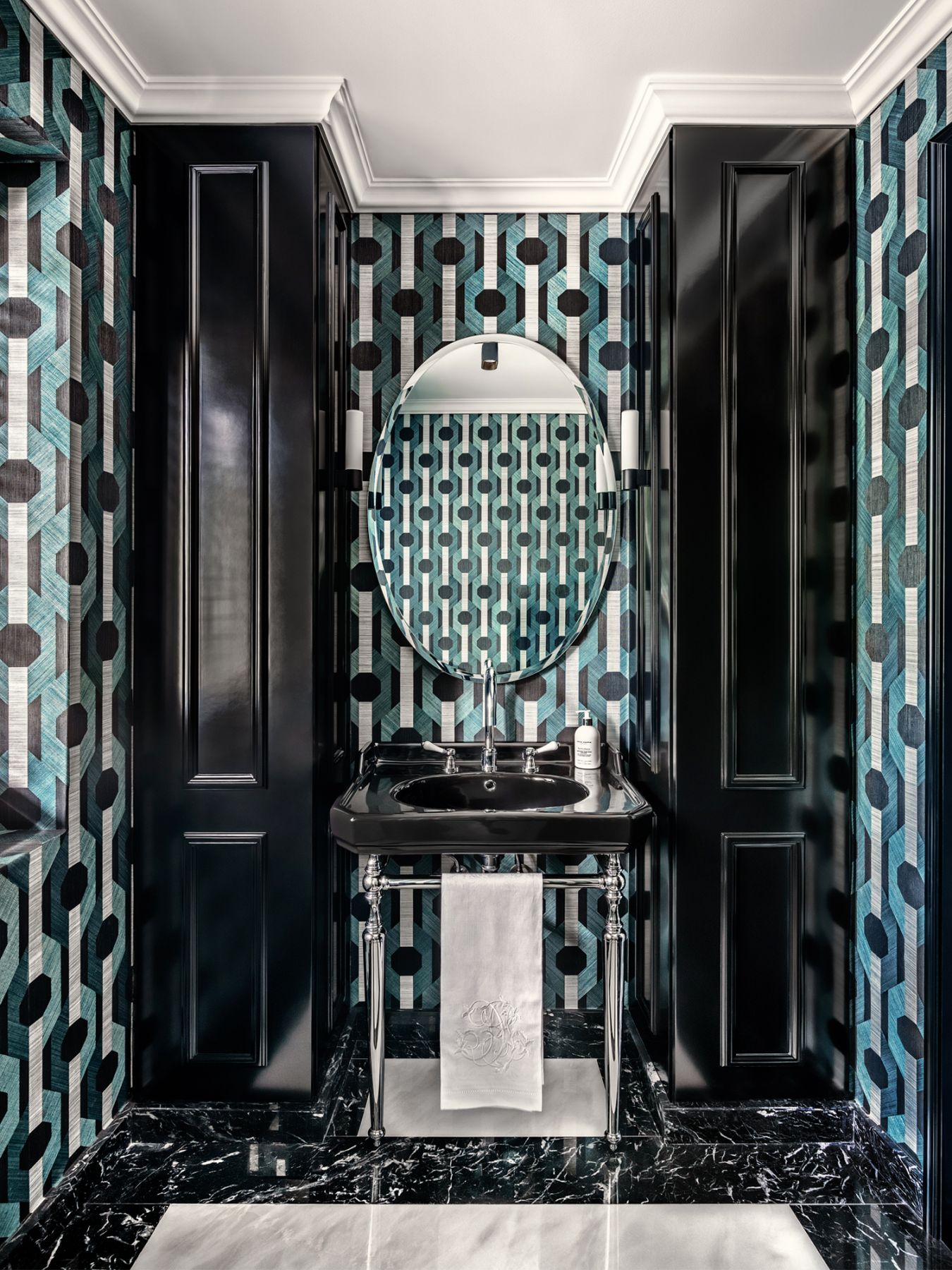 The powder room features the bold Oculaire wallpaper from Arte Internacional, and is furnished with a vintage Venetian mirror and the Bari wall light by Astro Lighting