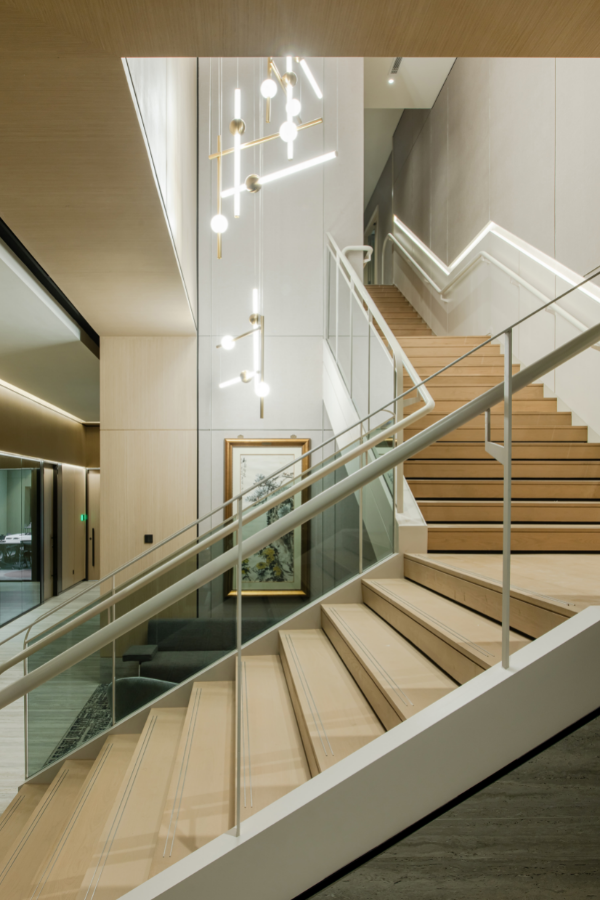 The refurbished staircase leading to the floor above has a glass railing on one side and recessed handle on the other.
