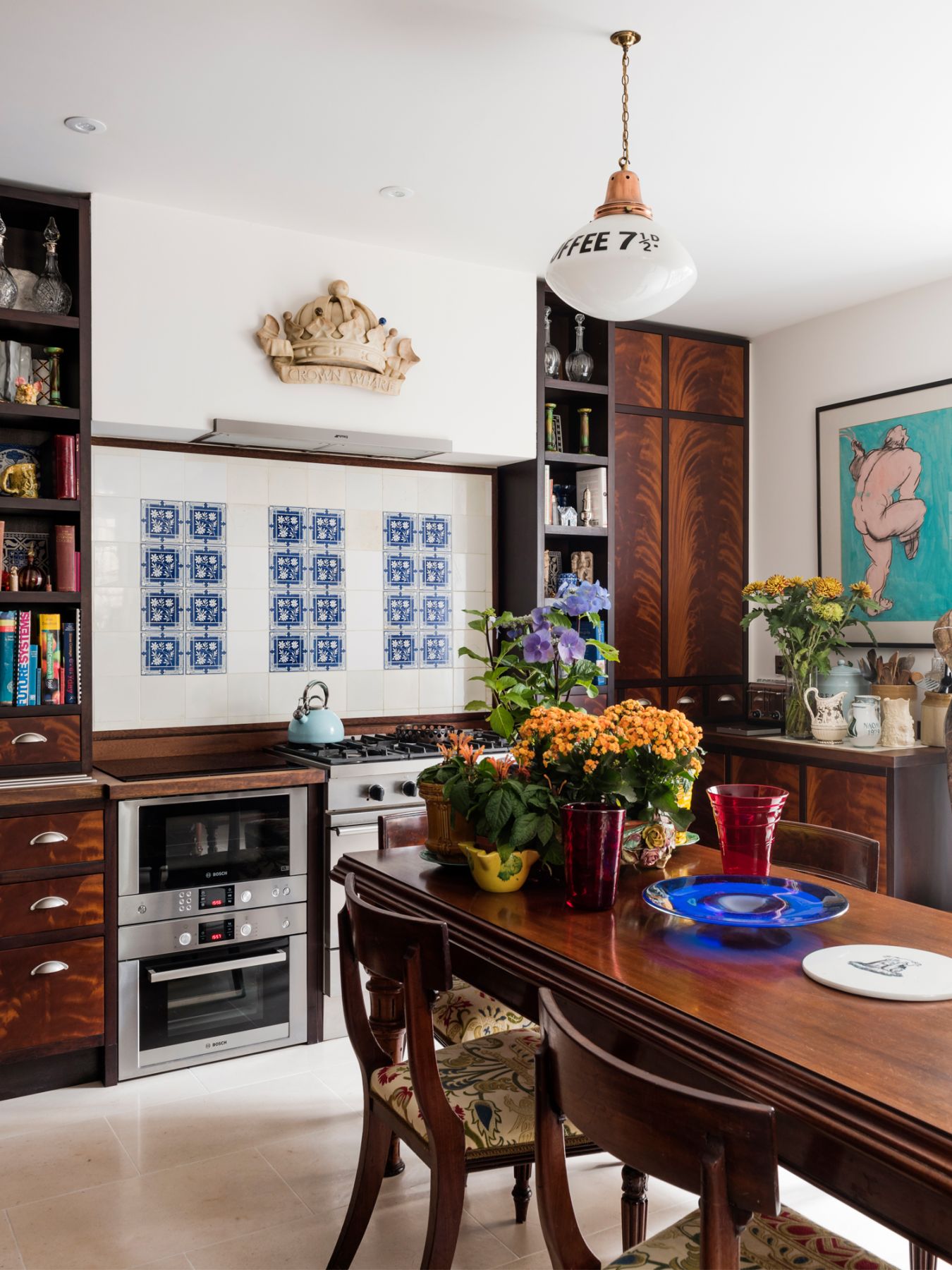 Flowers and artworks that decorate the walls enliven the space, alongside blue porcelain tiles that form the kitchen's backsplash