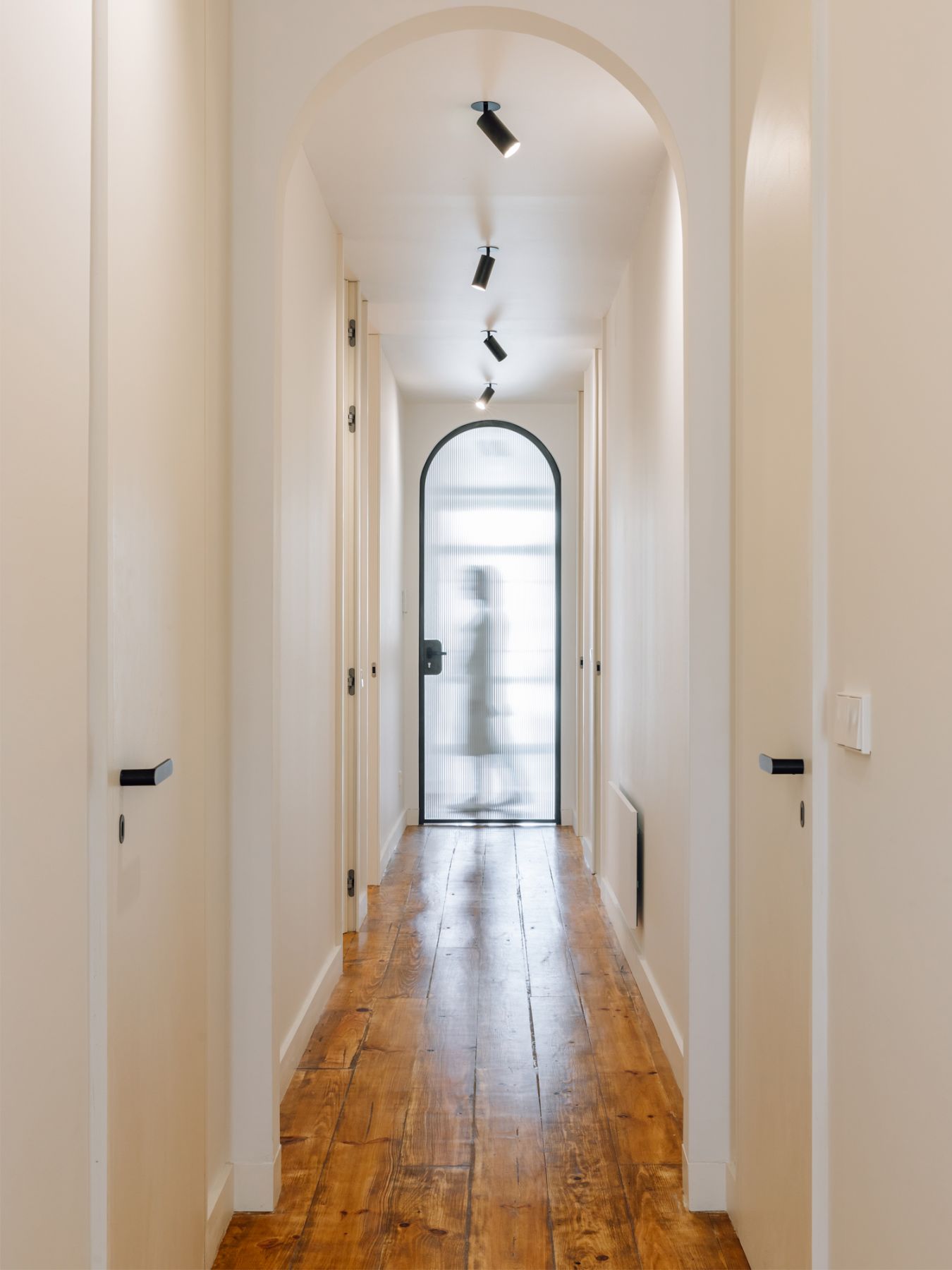 A fluted curved glass door at the end of the hallway segments the different spaces whilst adding visual interest