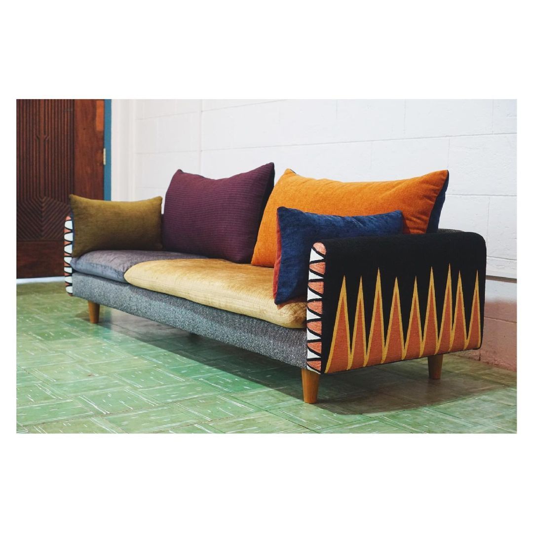 A low-lying compact sofa, upholstered in lush fabric with hand-painted details on the side