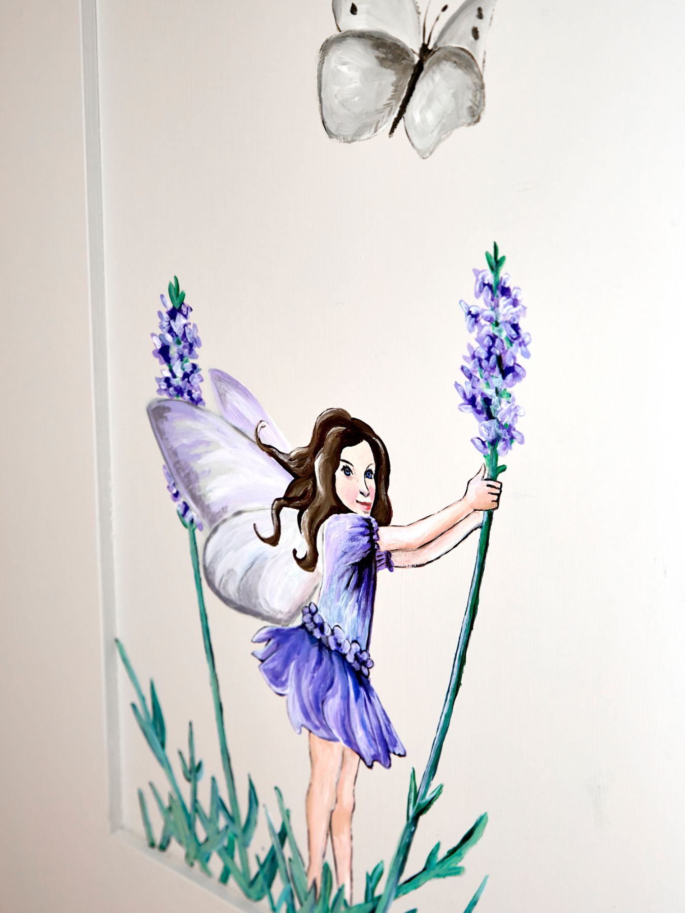 Hand-painted fairies on the wardrobe doors add a whimsical theme to the room