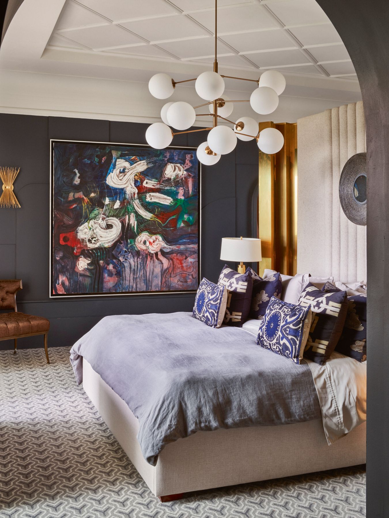 In the master bedroom, navy hues on the wall and bedlinen create a restful mood while highlighting the colourful painting by Ramón Oviedo