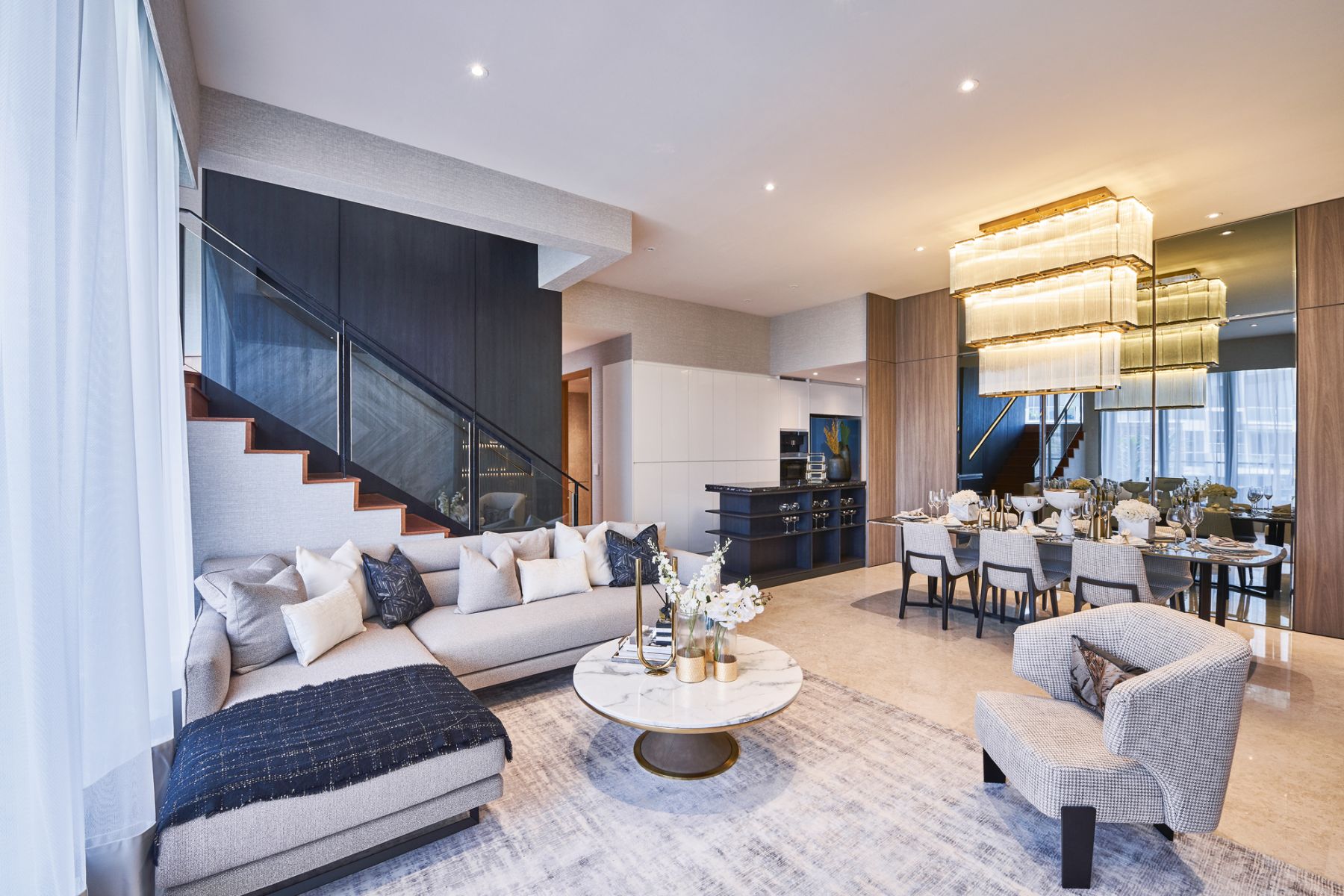 The dramatic three-tiered chandelier creates a focal point in this understated open-plan living and dining room