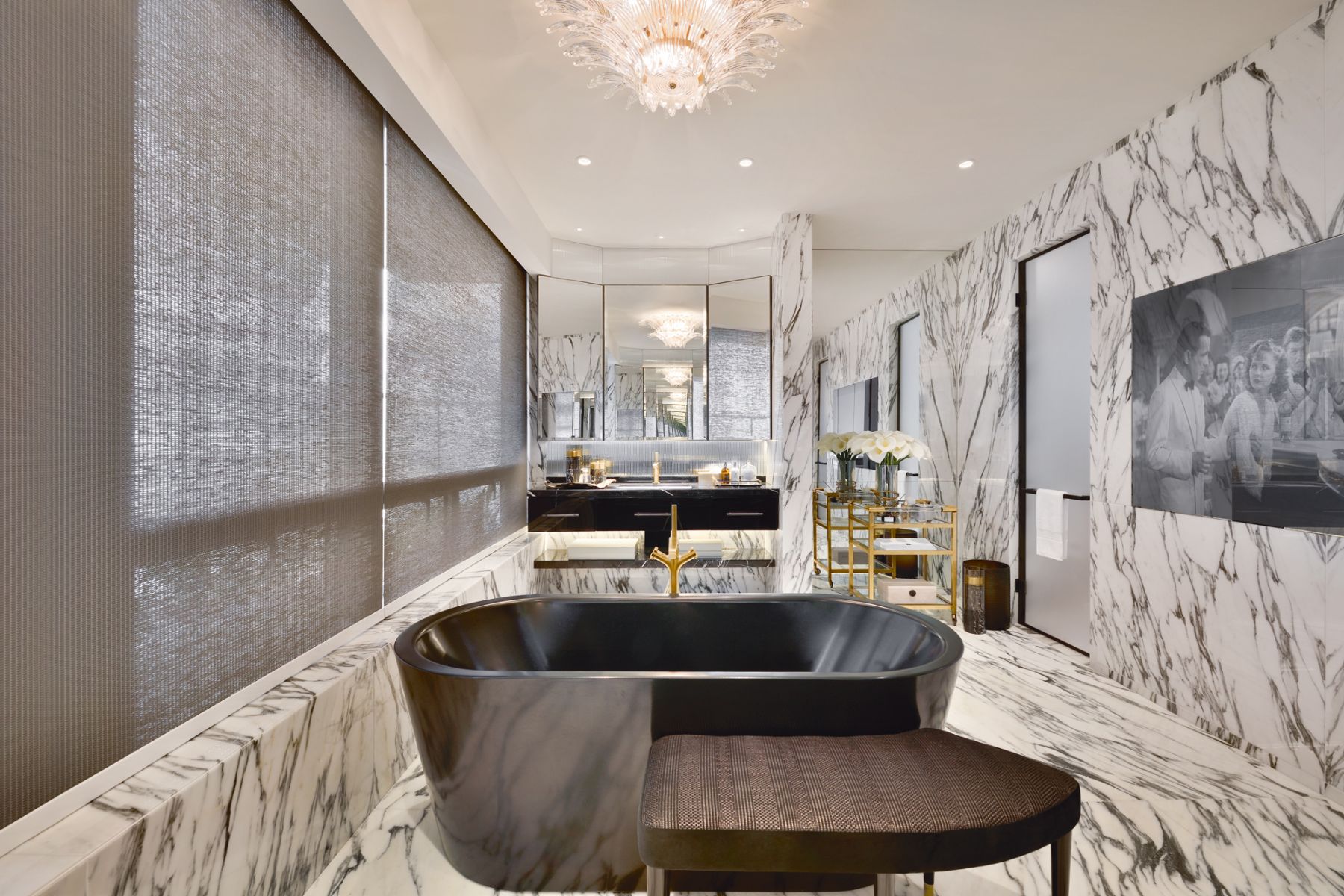 This opulent master bathroom features large-format marble tiles and a freestanding bathtub