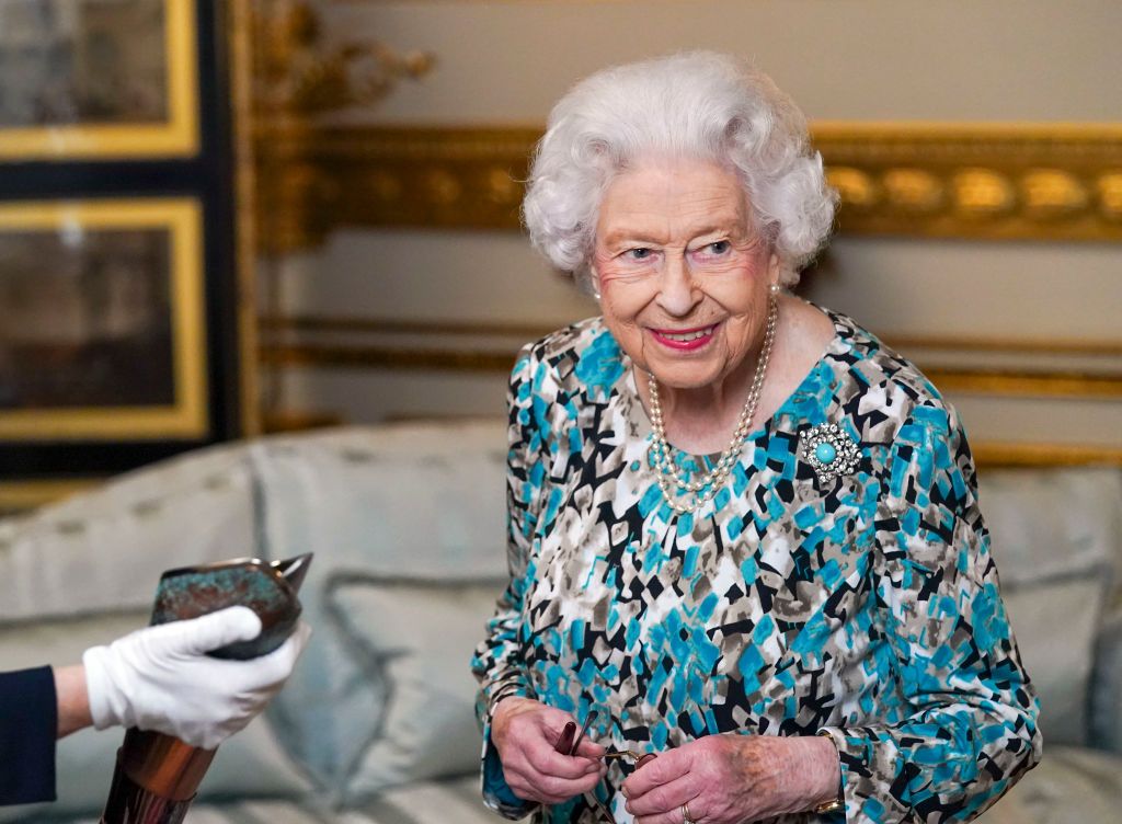 LONDON, ENGLAND - OCTOBER 07: Queen Elizabeth II looks at the Birmingham 2022 Commonwealth Games Baton during the Baton Relay for Birmingham 2022, the XXII Commonwealth Games at Buckingham Palace on October 7, 2021 in London, England. The baton will carry a message from Queen Elizabeth II throughout the relay, which starts at Buckingham Palace in London before 7,500 bearers take the baton on a 90,000-mile journey to all 72 nations and territories of the Commonwealth over 294 days. The Queen and The Earl of