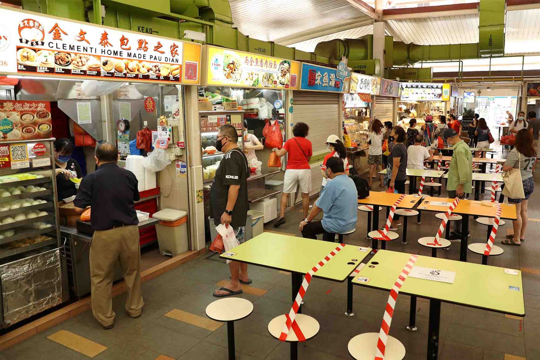 People queue up at a hawker center as tables are cordoned off. (Photo: Getty Images)