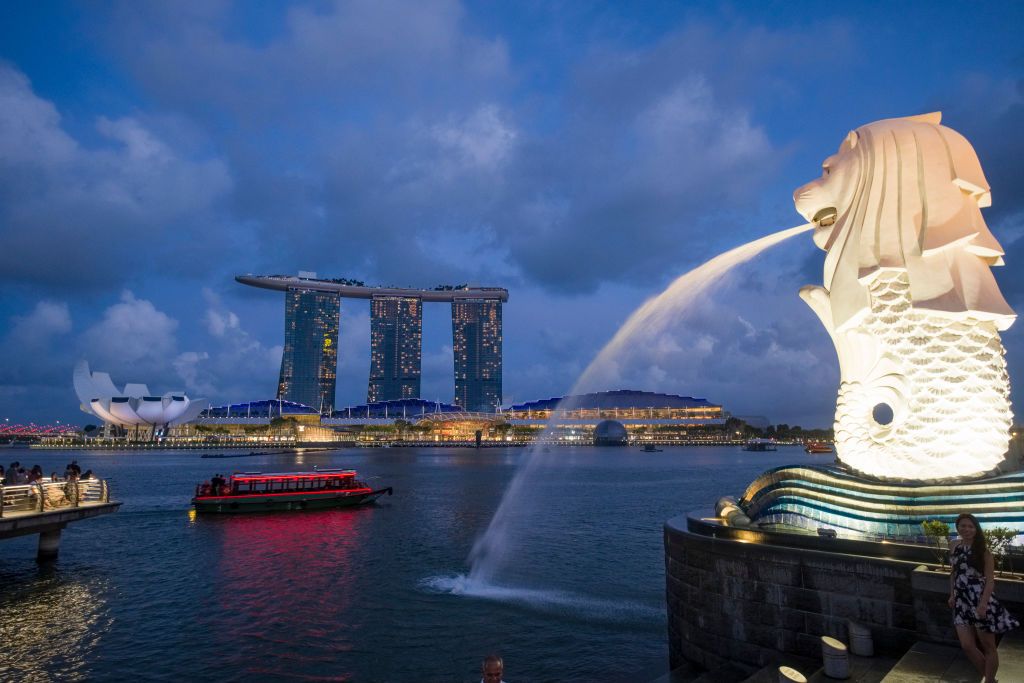 Singapore, the Merlion, statue representing a mythical creature with a lion's head and the body of a fish, in Marina Bay. In the background the Marina Bay Sands (hotel and shopping mall). (Photo by: Benard E/Andia/Universal Images Group via Getty Images)