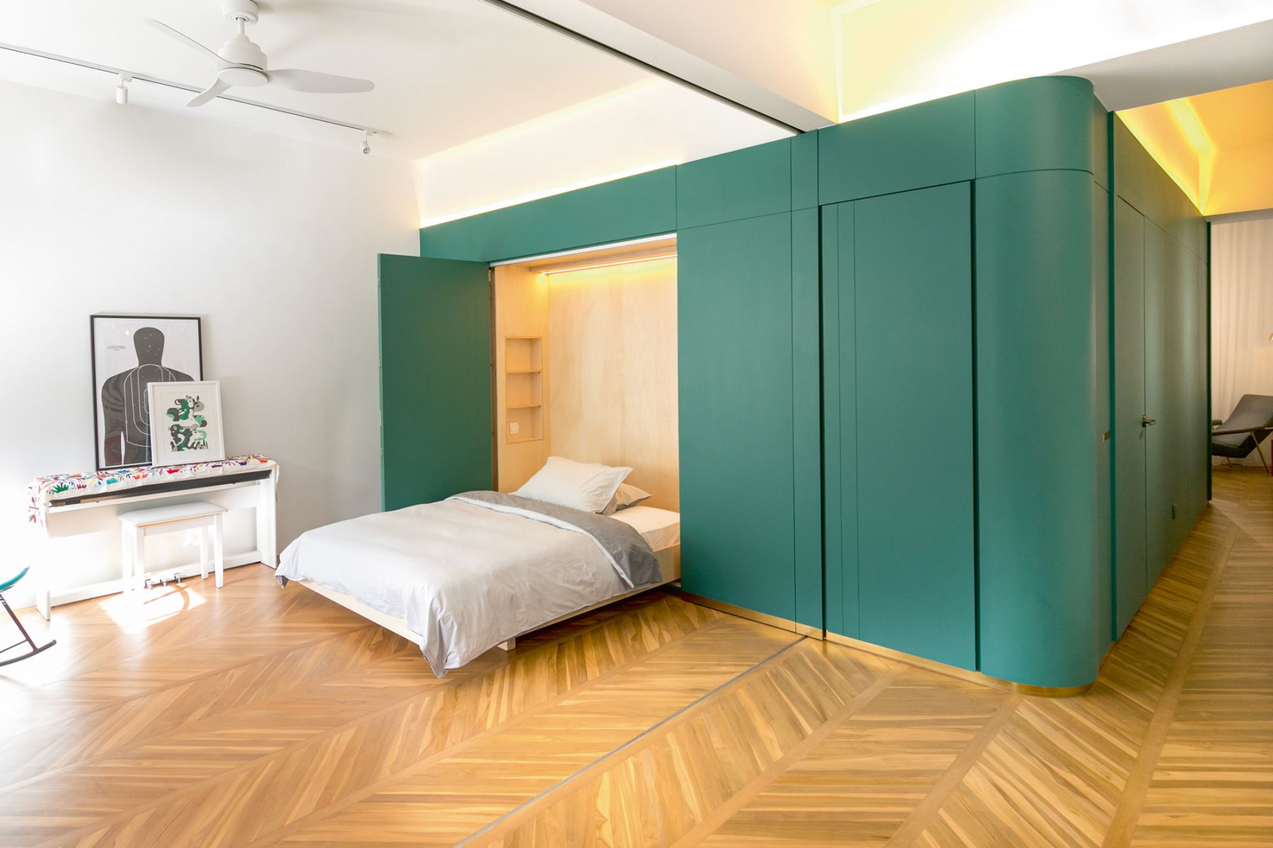 A fold-out bed can be extracted from the green cabinetry for visiting guests or stored within to allow for an uncluttered look