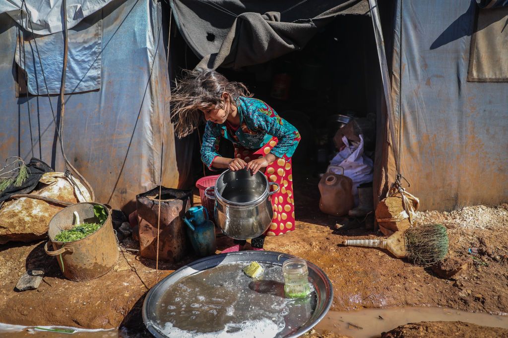 12 March 2021, Syria, Ma'arrat Misrin: A Syrian girld cleans a cooking pot in front of her tent at a refugee camp for internally displaced people in the town of Ma'arrat Misrin. Since the beginning of the Syrian civil war 10 years ago, at least half a million people were killed, more than a million injured, while half of the country's population went into displacement. Photo: Anas Alkharboutli/dpa (Photo by Anas Alkharboutli/picture alliance via Getty Images)