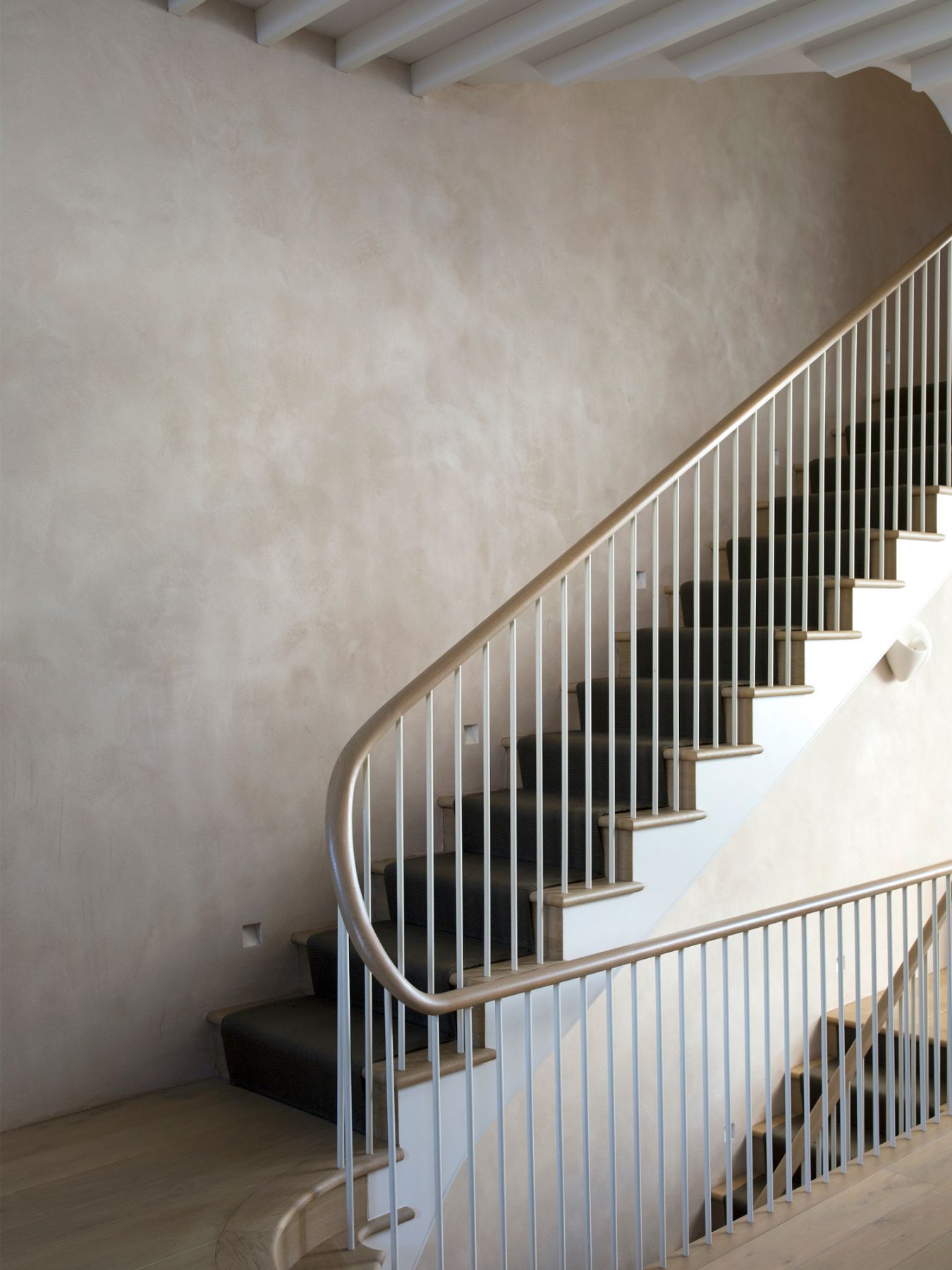 A continuous timber handrail runs throughout the house, uniting each room
