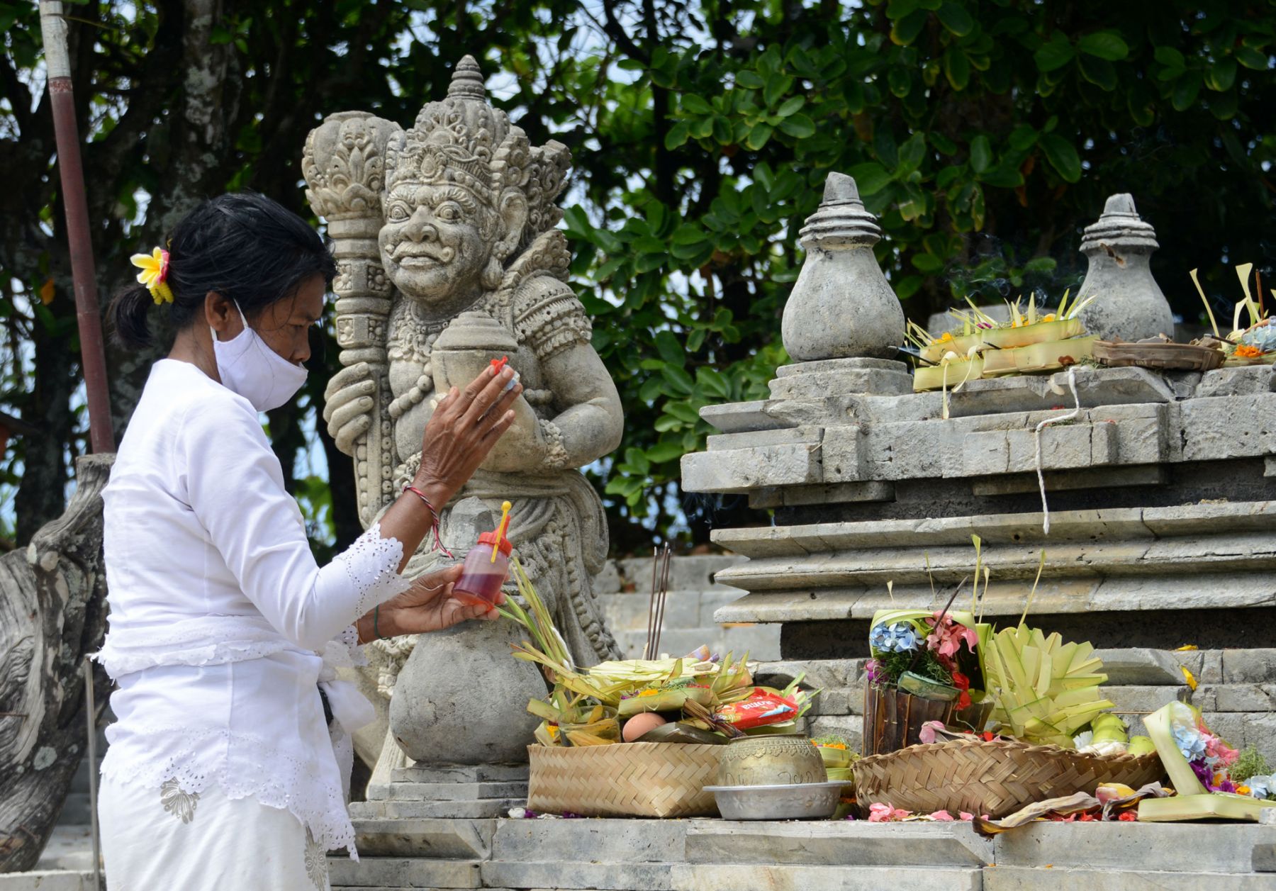 A Balinese woman prays at a temple in Uluwatu, in Badung regency on Indonesia's resort island of Bali on October 17, 2021. (Photo by SONNY TUMBELAKA / AFP)