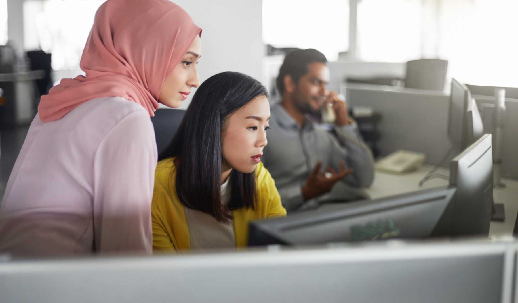 Businesswomen discussing over desktop PC in office. Female colleagues are looking in computer monitor. They are at workplace. (Businesswomen discussing over desktop PC in office. Female colleagues are looking in computer monitor. They are at workplace