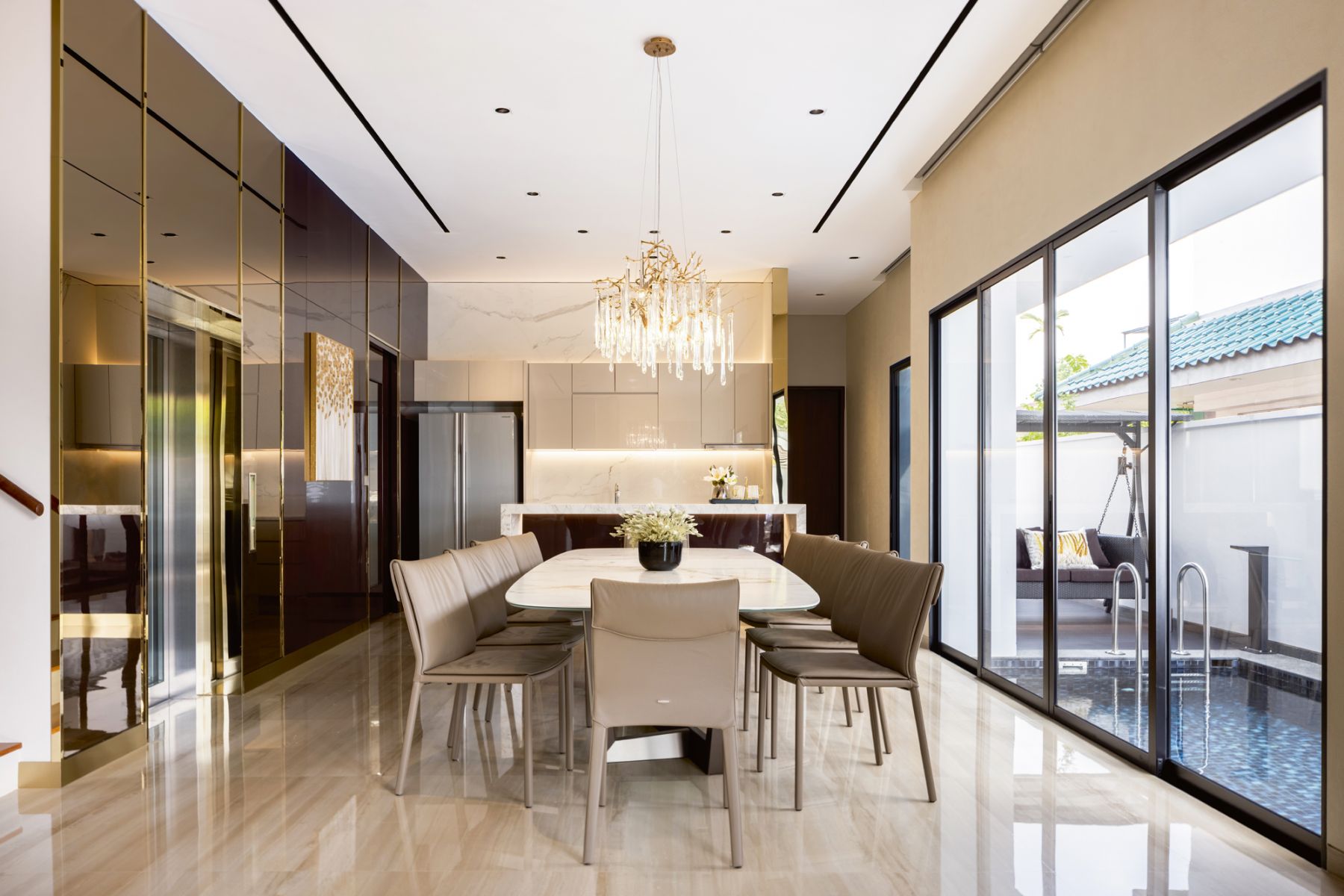 Glossy lacquered walls and bronze-tinted mirrors create a glamorous look in the dining area, where a Serip chandelier floats overhead