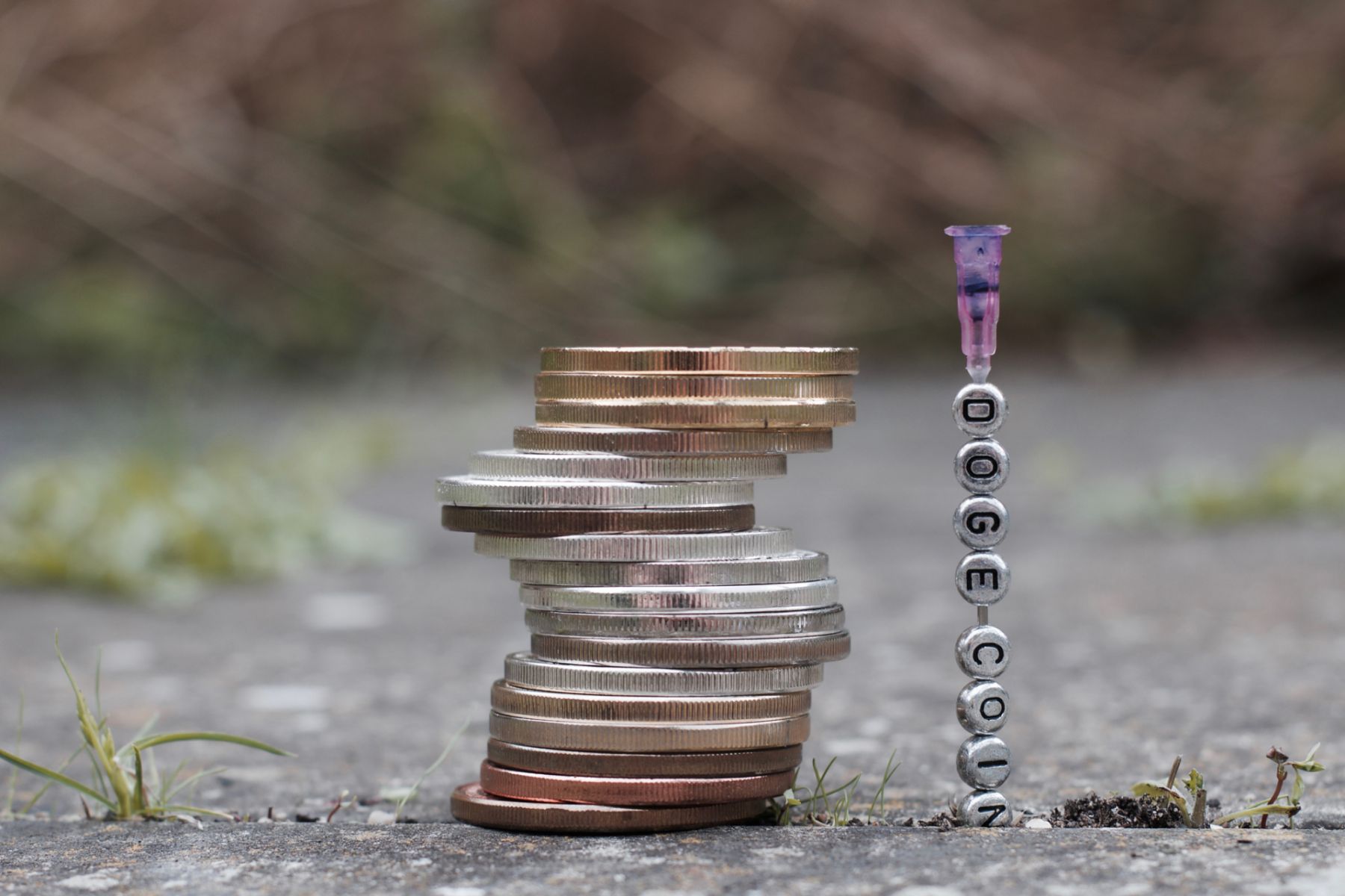 Digital currency physical silver and gold coins near needle with doge coin inscription.