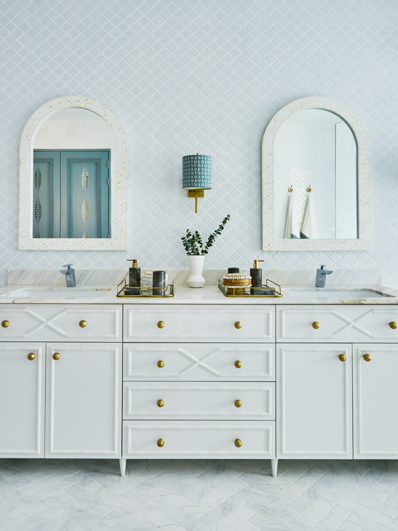 Textured door panels and metal hardware add visual interest to the vanity area of a bathroom designed by E&A Interiors