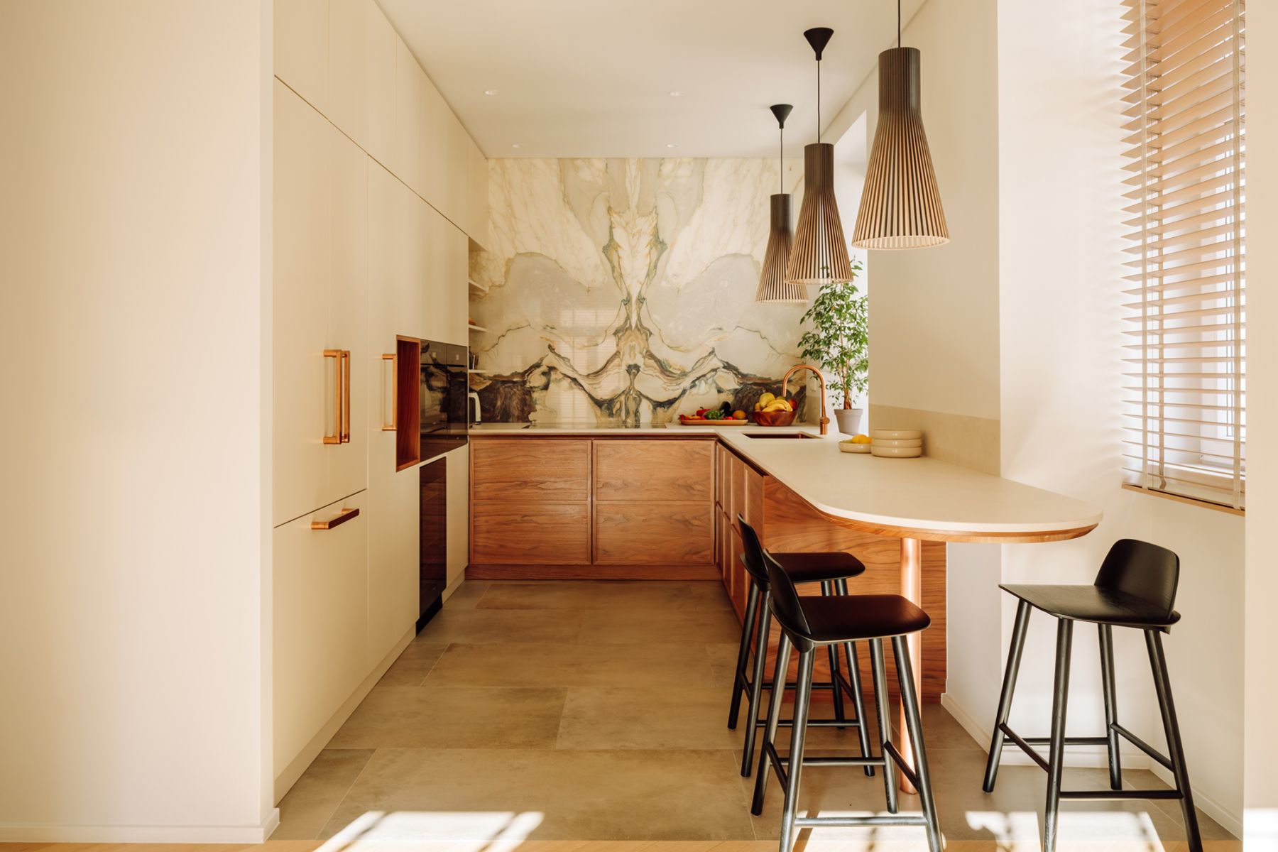 The elegant kitchen features a cosy breakfast bar with large windows offering natural light and an enviable view