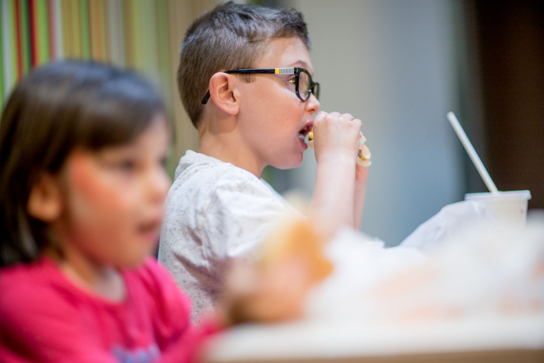 Niño comiendo hamburguesa en Mc Donalds al lado de su hermana