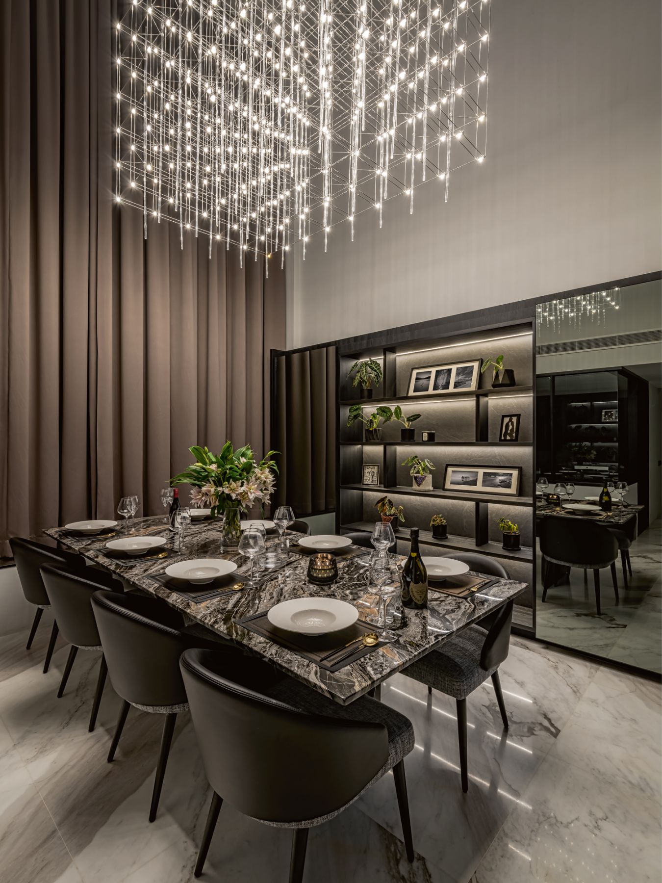Backlit shelves filled with house plants and personal mementos create a graceful backdrop in the dining area