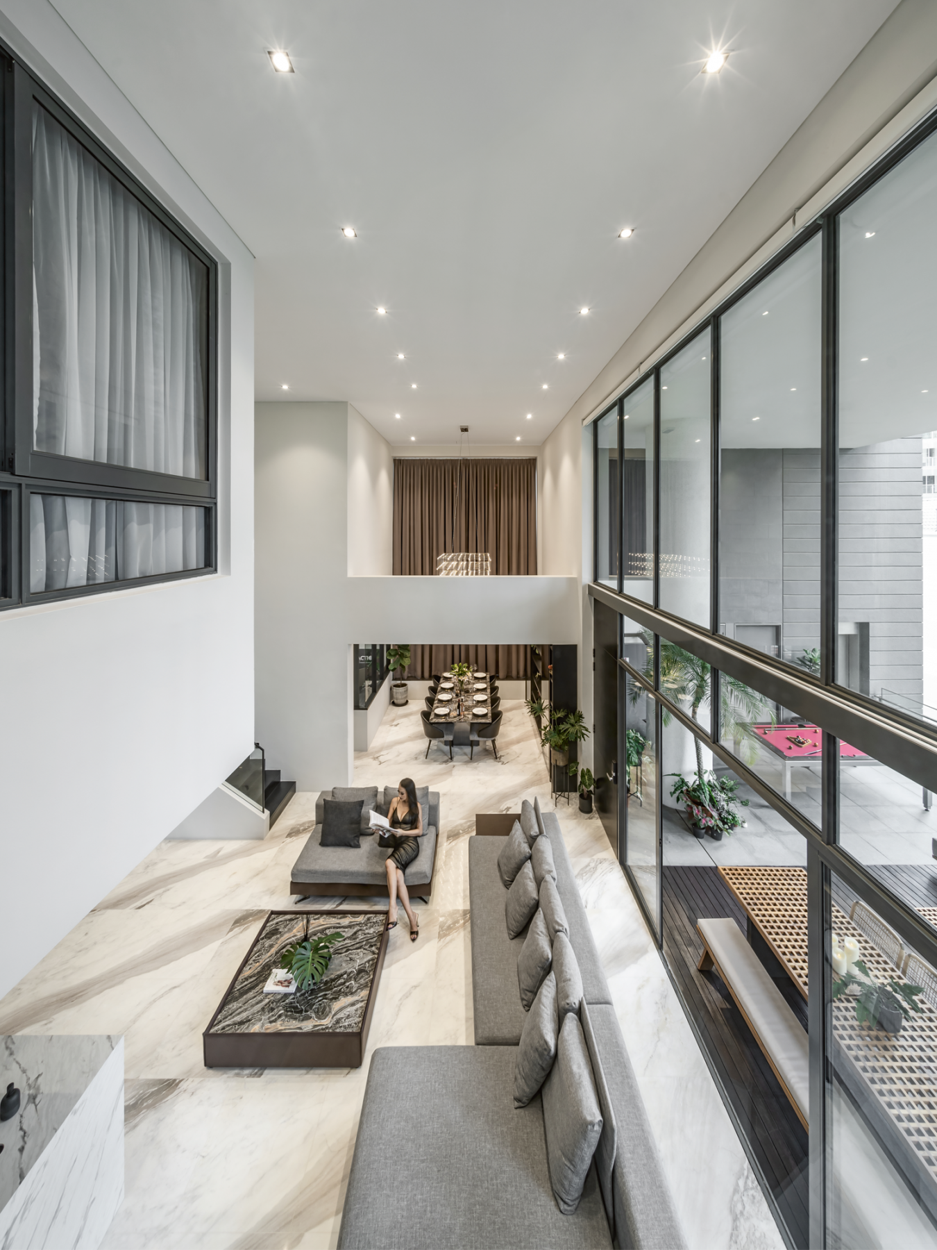Grey sectional sofas visually demarcate the huge open-plan living area from the dining zone