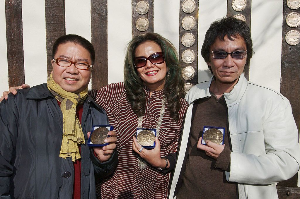 Deauville, FRANCE: (From left to right) Chinese director Fruit Chan, Indonesian actress and director Christine Hakim, and Japonese director Takashi Miike pose after receiving decorations from city's mayor Philippe Augier, 12 March 2005 in Deauville, at the 7th Asian Film Festival. AFP PHOTO MYCHELE DANIAU (Photo credit should read MYCHELE DANIAU/AFP via Getty Images)