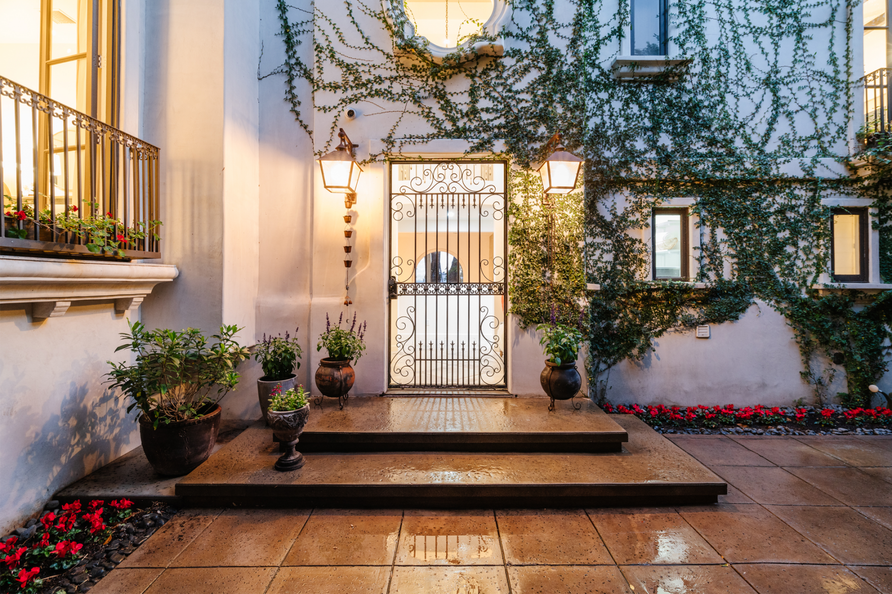 The front of the home features an iron-wrought gate and crawling wall vines