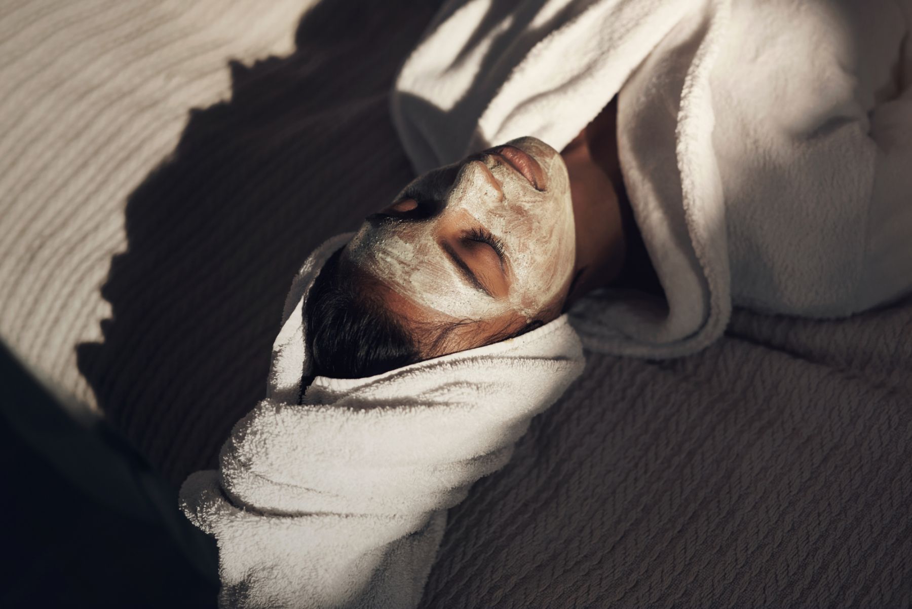 Shot of a young woman giving herself a facial at home