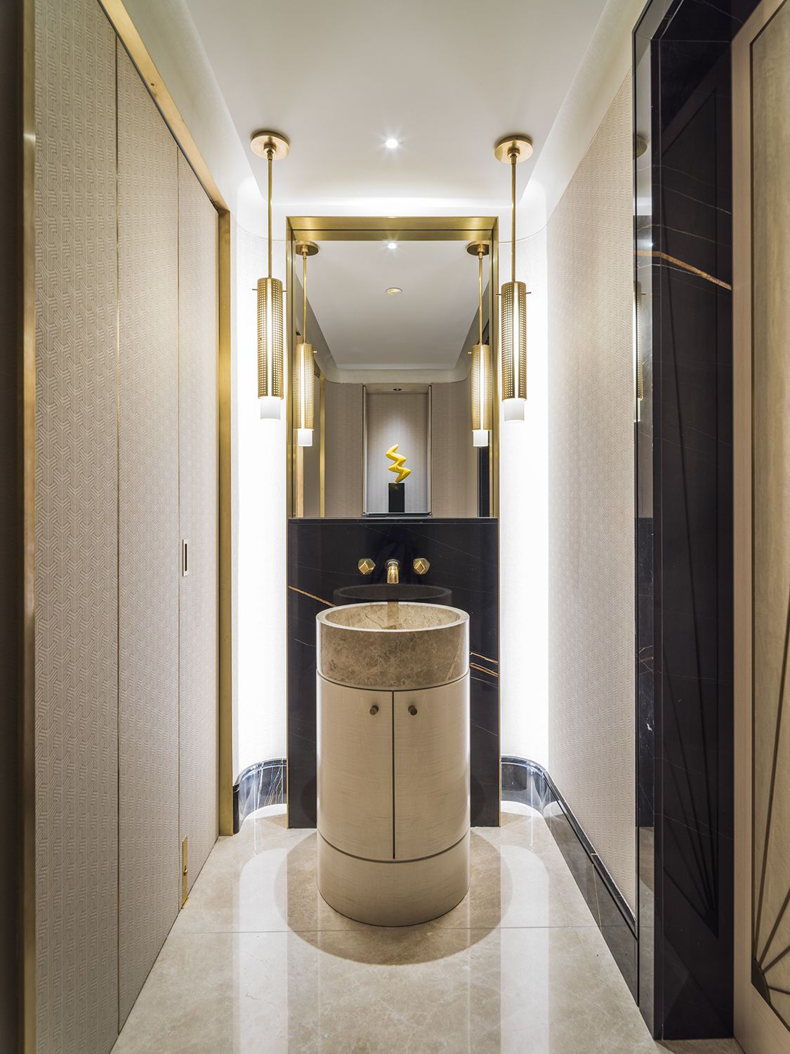 The stunning powder room features a sculptural, circular vanity, together with bijou hanging pendant lights and brassware