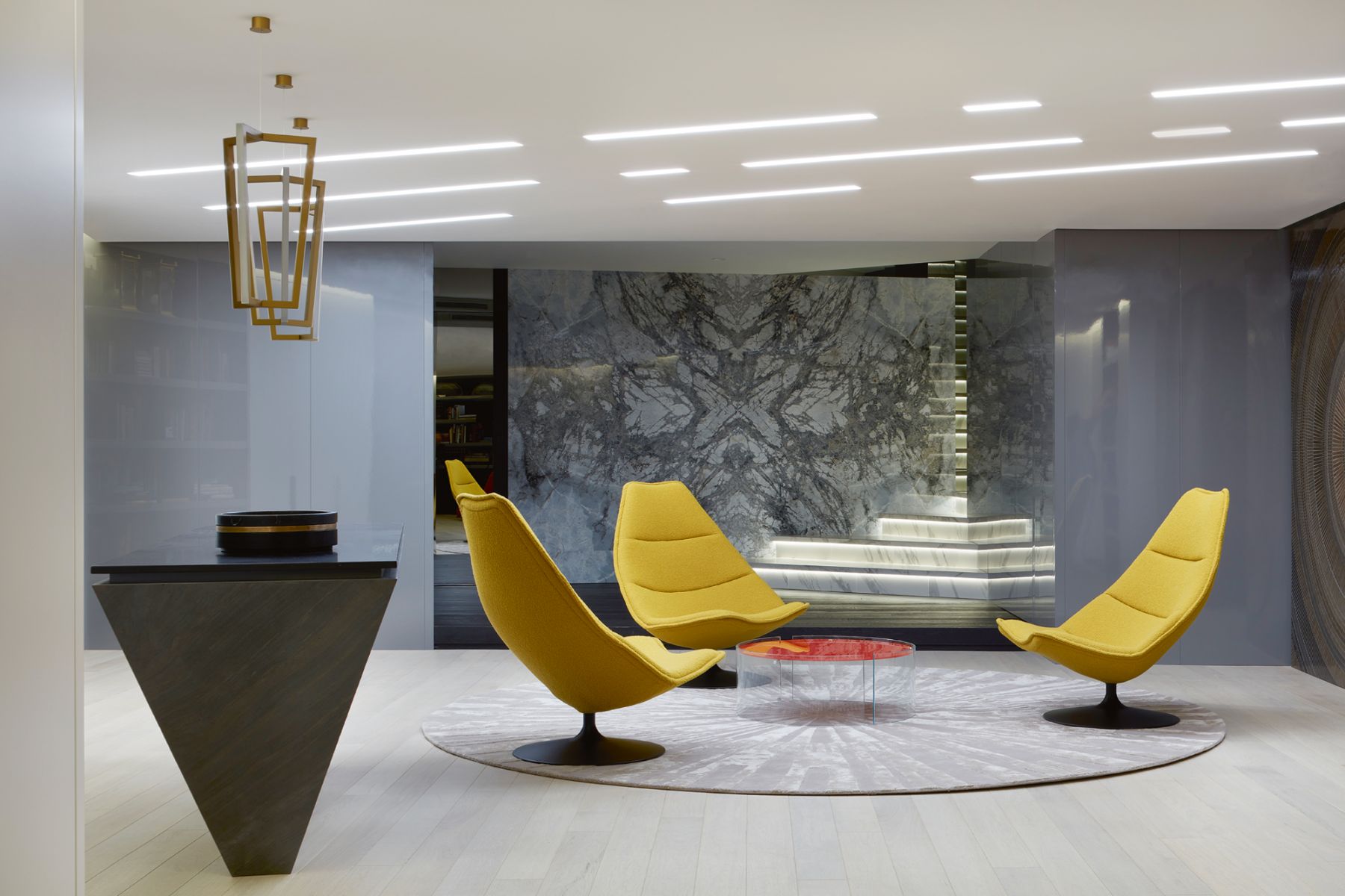 Yellow Artifort armchairs, backlit marble steps and the striking veins of the marble feature wall add a dose of drama to this lounge area