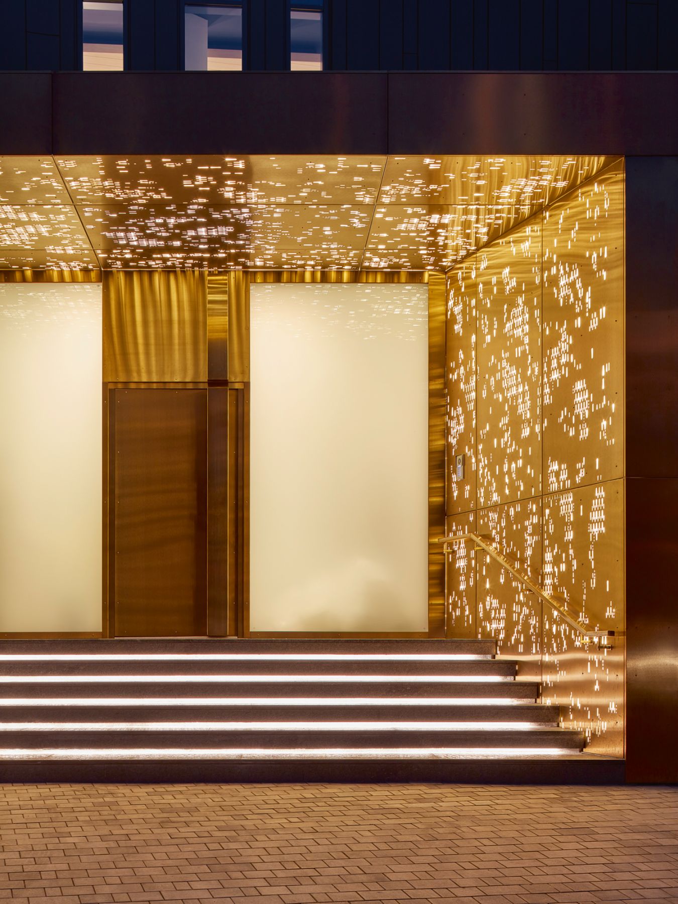 The backlit, bronze-clad entrance hints at the glamorous interiors within the abode