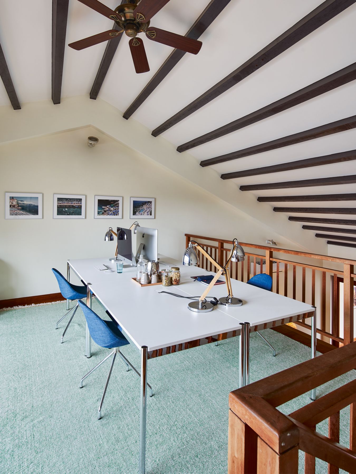 The home office enjoys ample daylight, and features photos of seaside towns accompanied by a monochromatic palette that draws inspiration from nature